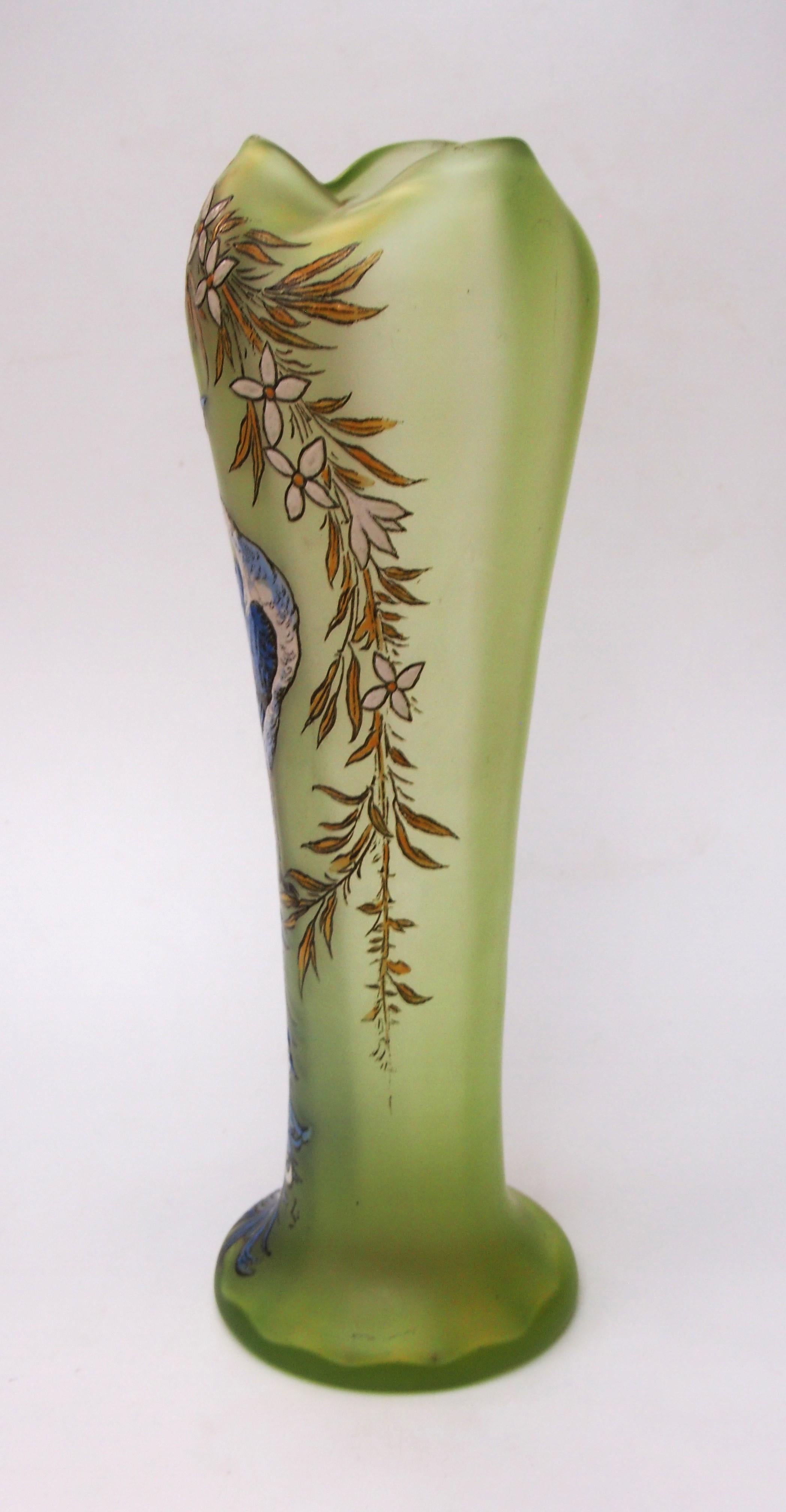 Drammatico vaso monumentale policromo di Legras a forma di balaustro allungato con piede strombato e piano tornito a forma di tre. Il colore del vetro è un vibrante verde uranio. L'immagine raffigura un pavone alto e drammatico in blu e bianco