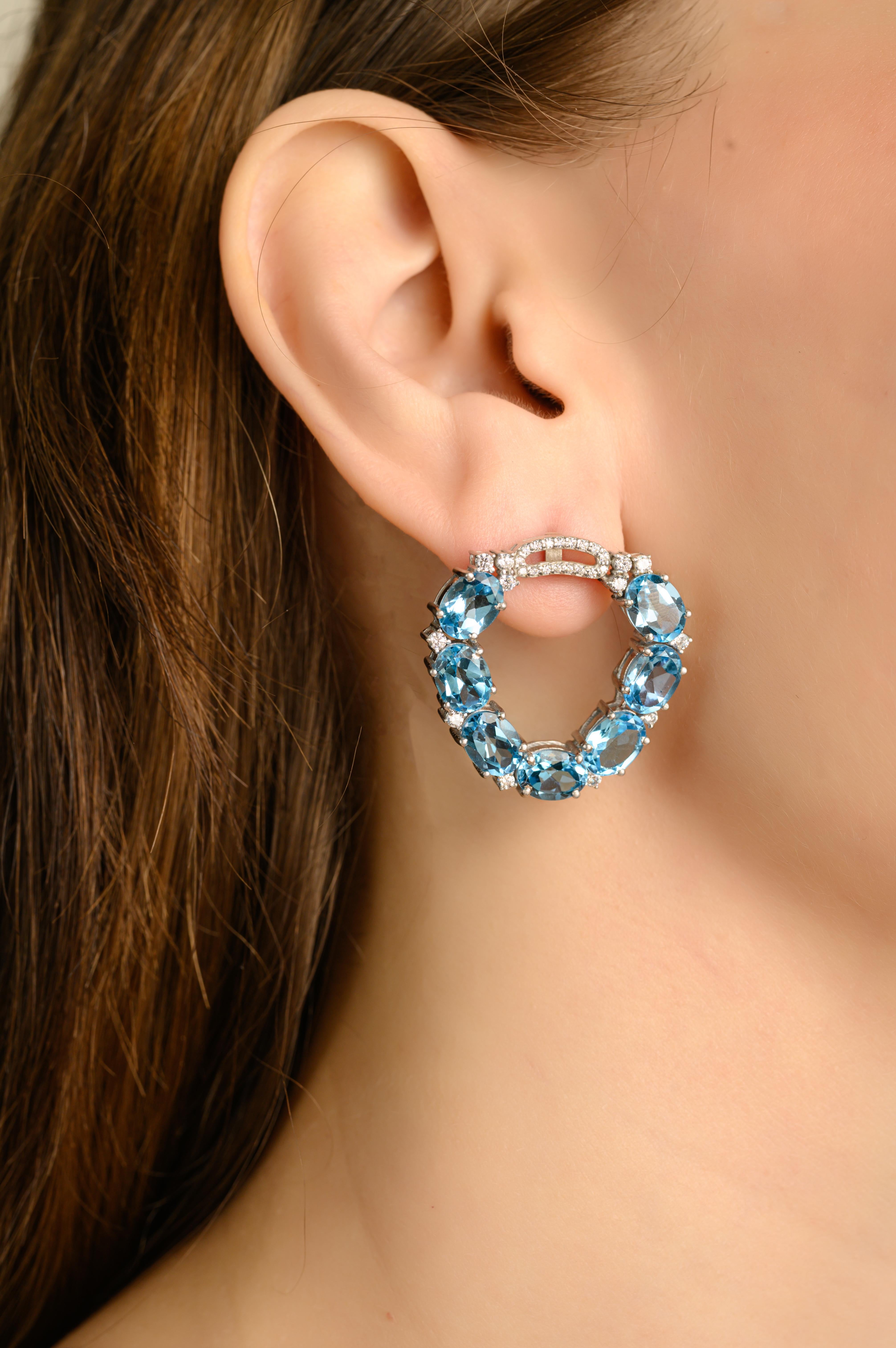 Diese glänzenden Verlobungsohrringe mit blauem Topas und Zirkon sind aus feinem 925er Sterlingsilber gefertigt und mit natürlichen blauen Topas-Edelsteinen im Ovalschliff verziert, die ein fesselndes ozeanblaues Funkeln verbreiten. Jeder Edelstein