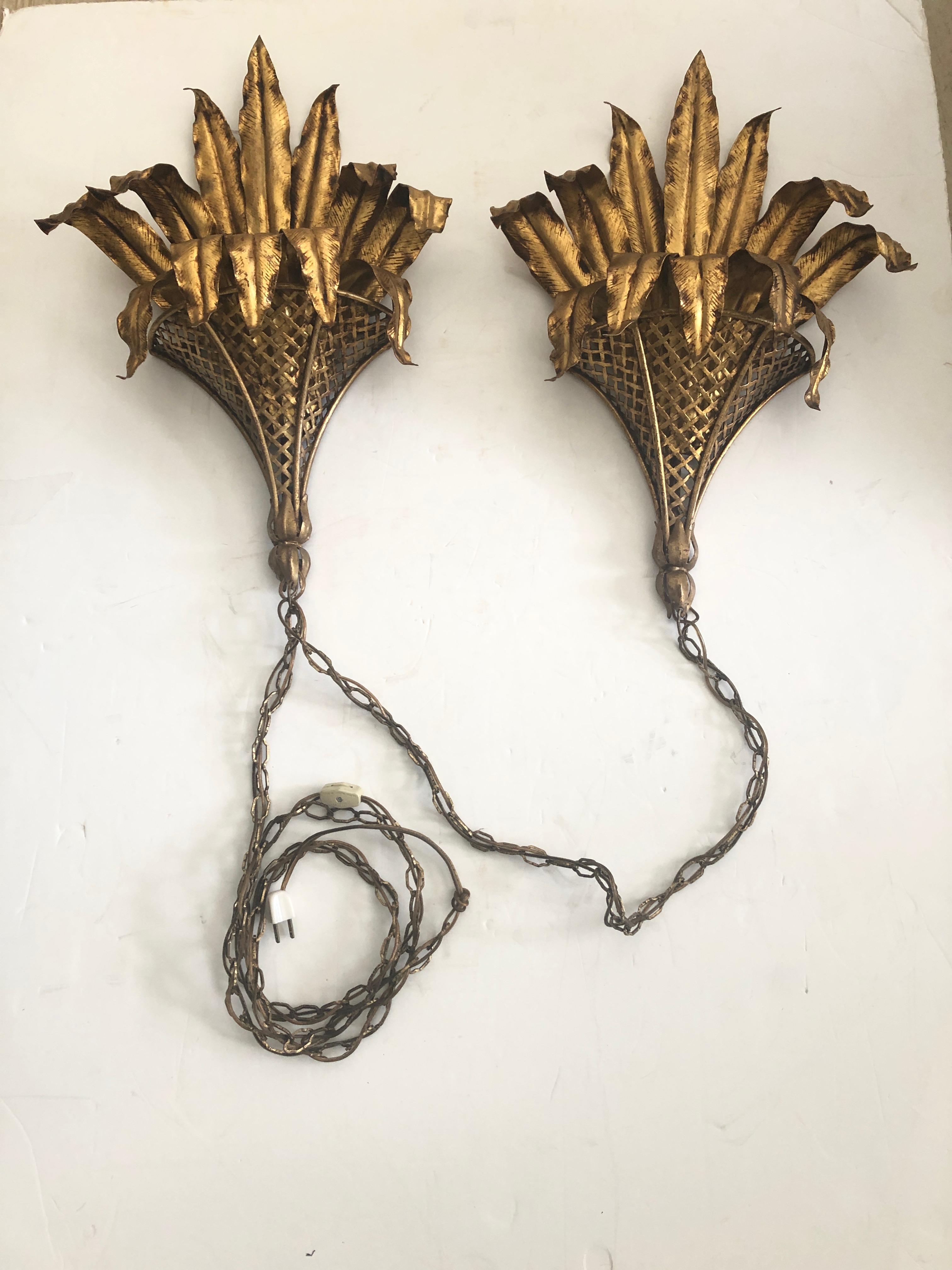 Fabulous pair of gilt iron leafy electrified sconces having sculptural banana leaf foliage pouring forth from basket weave brackets. Connected by 30