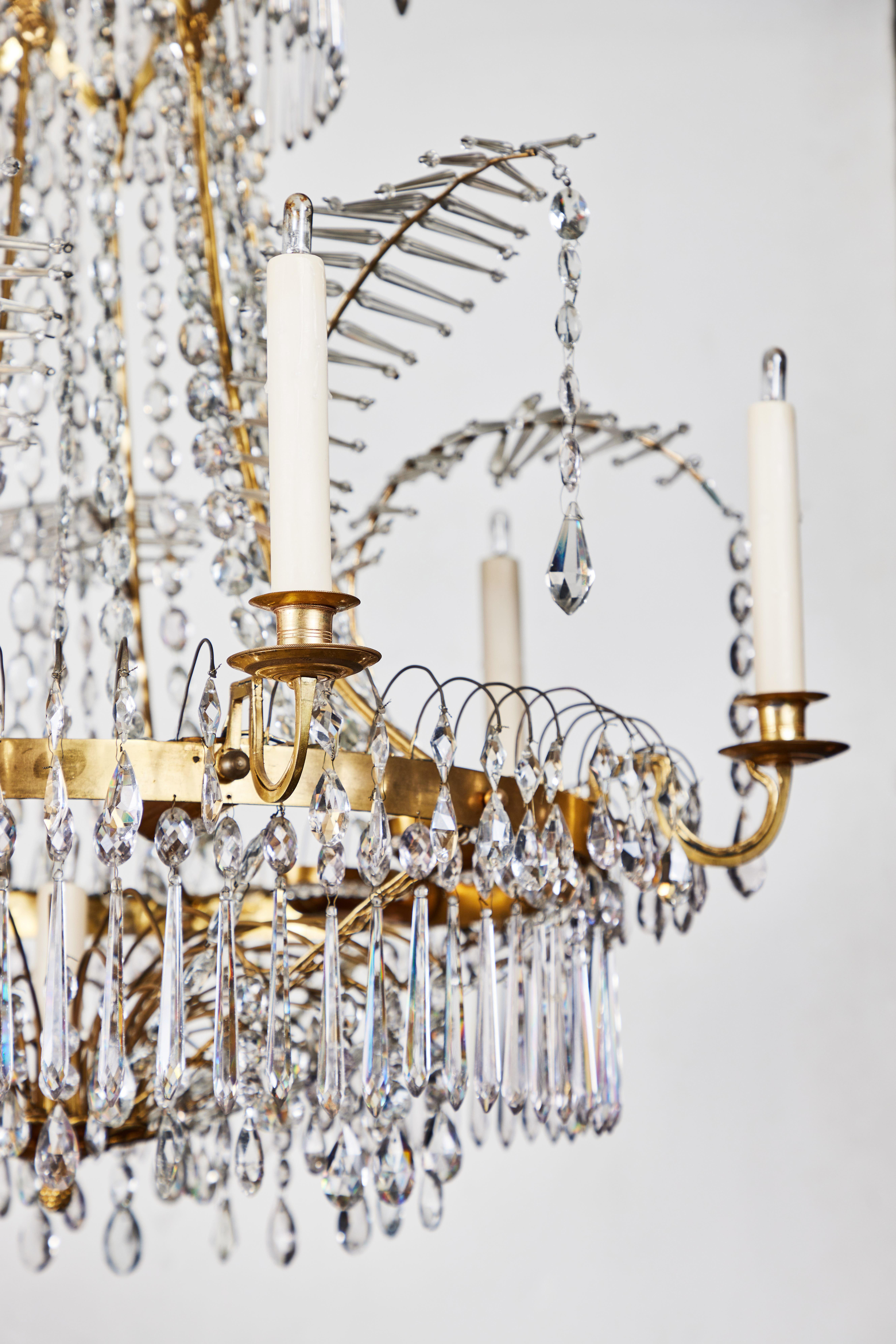 A beautifully designed, circa 1930, six-arm chandelier dripping in cut crystal. The gilt bronze carriage is lit internally by an additional eight lights, and features delicate tendrils that spring outward to arching, crystal, frond style