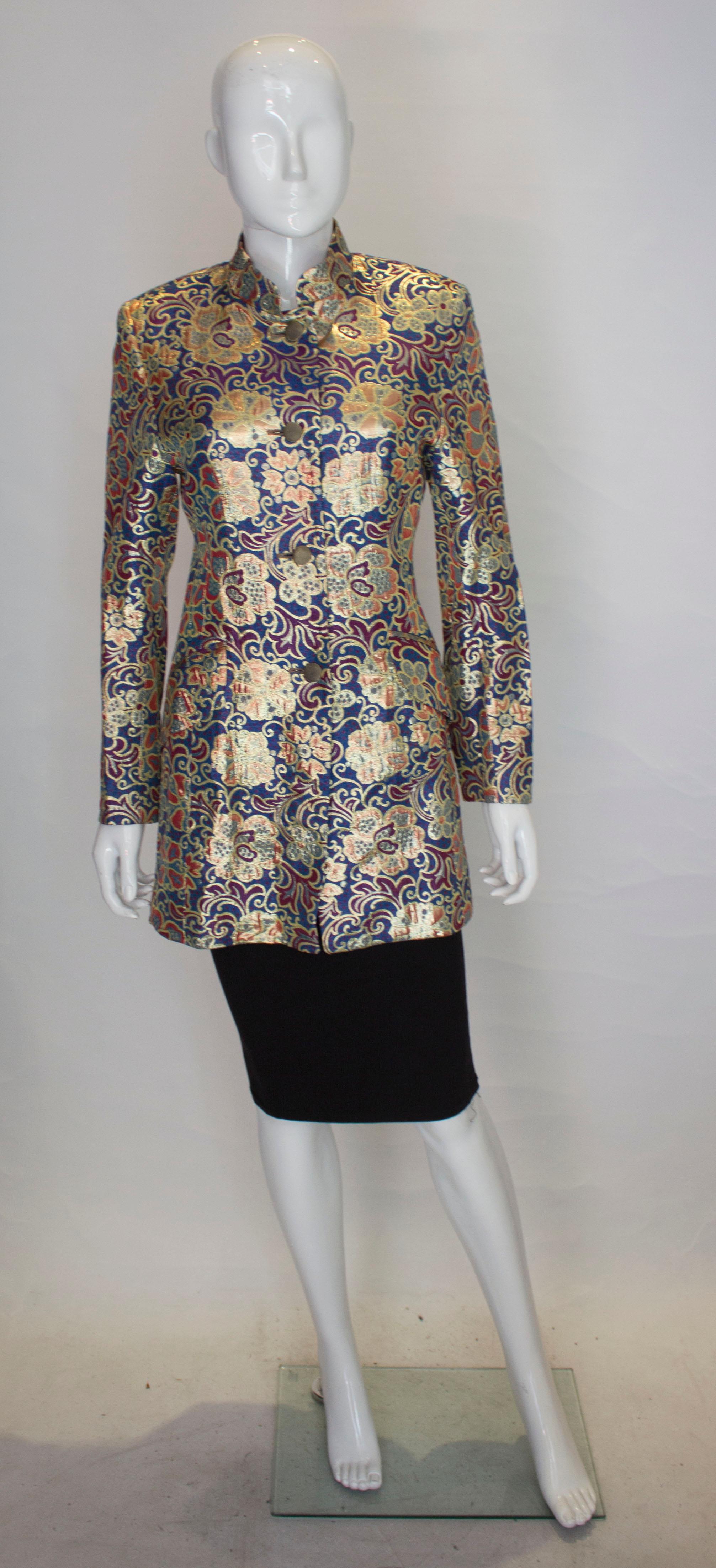 Une veste qui fait tourner la tête, signée Selina Blow. Dans un  magnifique mélange d'or, de bleu, de bordeaux et de vert, la veste a un col montant et une ouverture sur le devant.