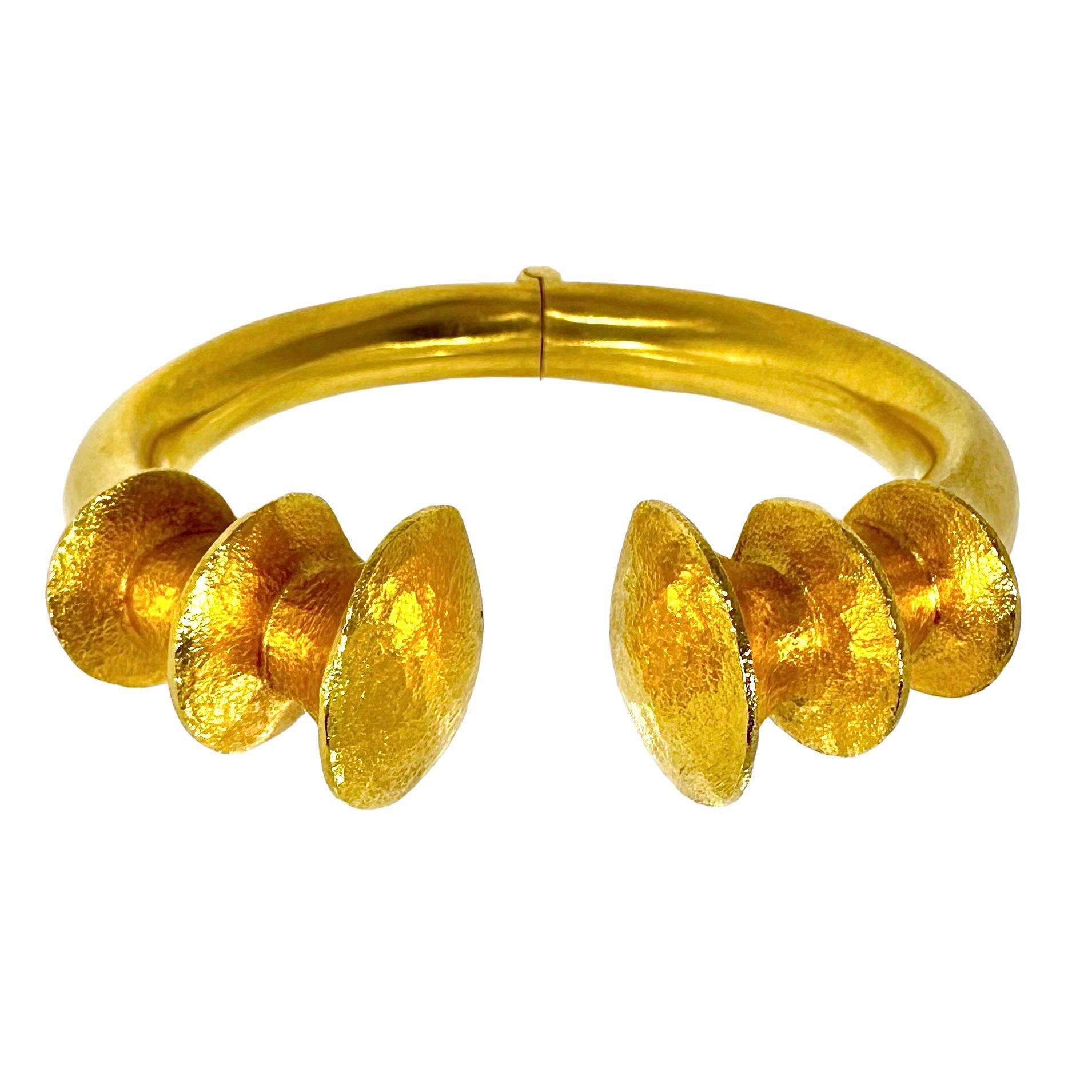 This very dramatic Ilias Lalaounis hinged 22k yellow gold bangle bracelet is a true departure from the venerated Greek jewelers usual style. A wonderful satin finish body terminates at the front in six delicately hammered finish soaring arches. The