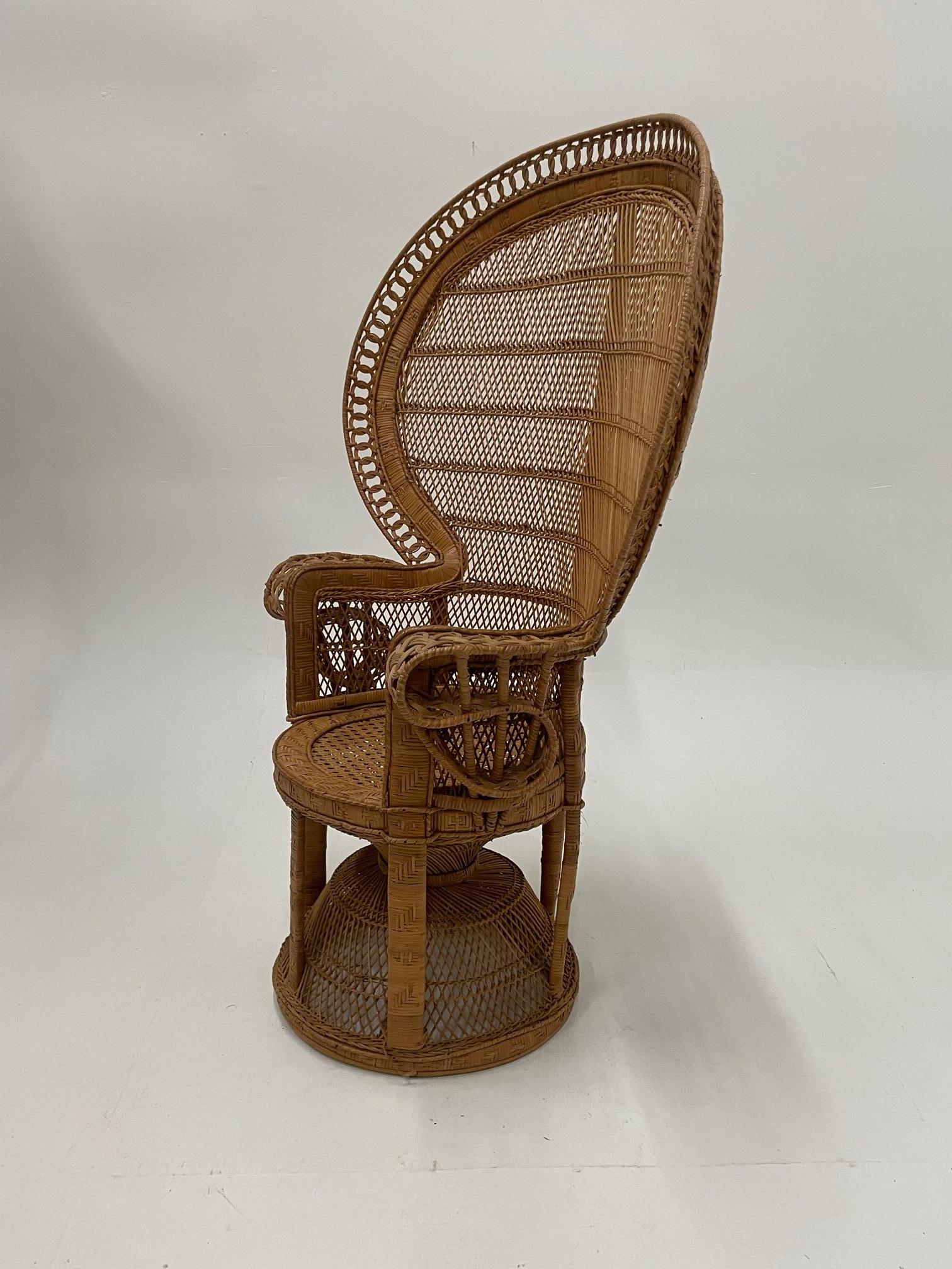 Une chaise en rotin en forme de paon qui attire l'attention par sa forme et son style iconiques.
Mesure : Hauteur des bras 29.