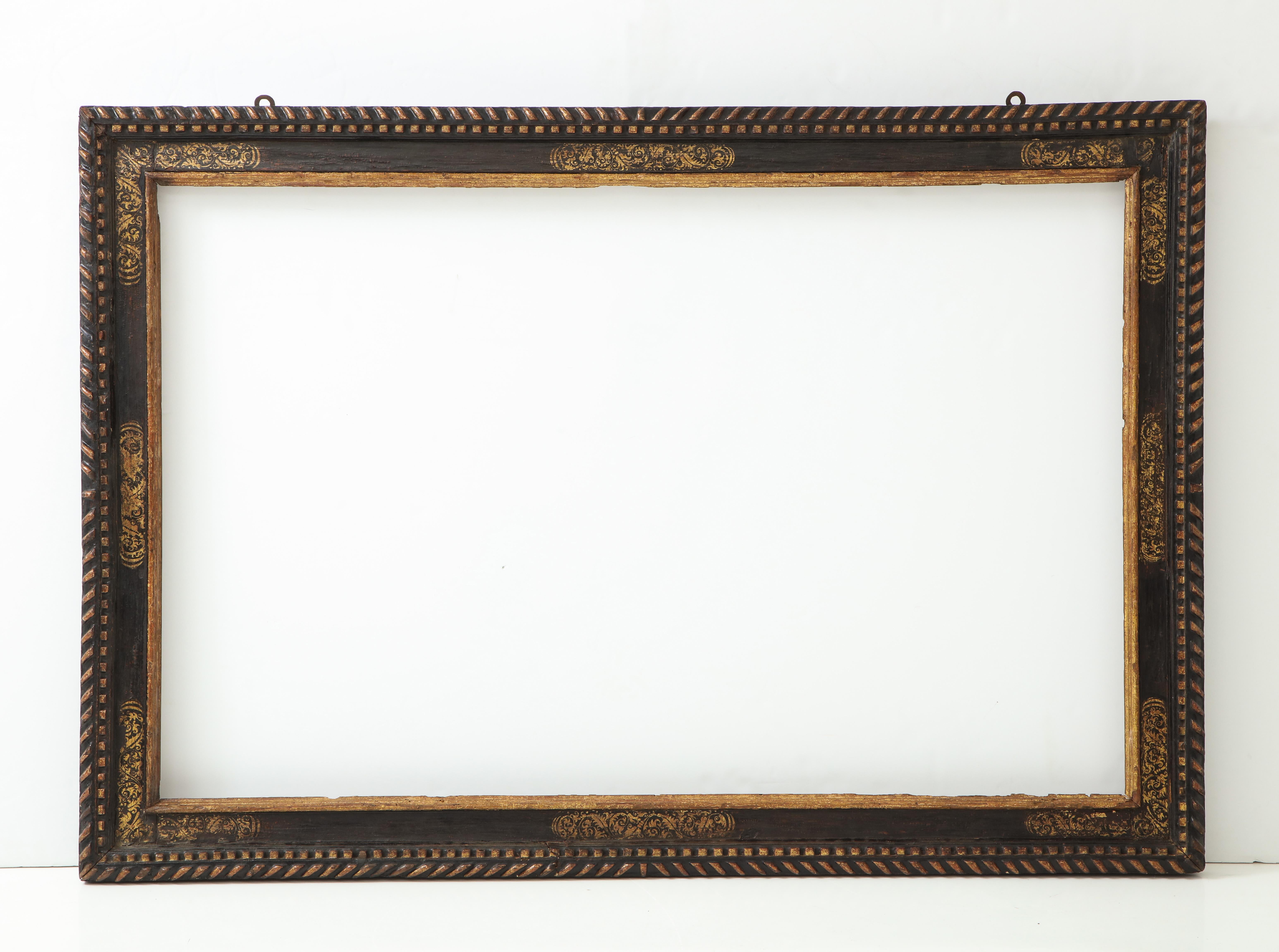 A dramatically large carved, gilded and polychrome Spanish Baroque period frame.

The top edge decorated with carved gadroons; the black polychrome frieze decorated with estofado (the layering of gold or silver leaf over a gesso base, followed by an