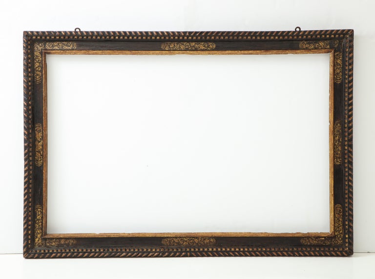 A dramatically large carved, gilded and polychrome Spanish Baroque period frame.

The top edge decorated with carved gadroons; the black polychrome frieze decorated with estofado (the layering of gold or silver leaf over a gesso base, followed by an