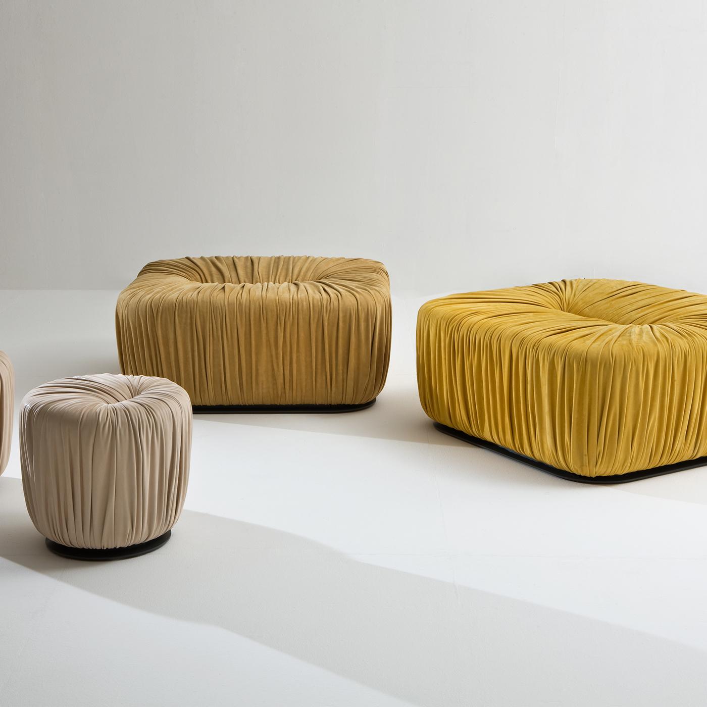 This luxurious rectangular ottoman is upholstered in soft yellow nubuck leather and is also available in several other shapes and sizes. The Drapé Collection is a set of upholstered poufs covered in leather or velvet with a base in metal, whose