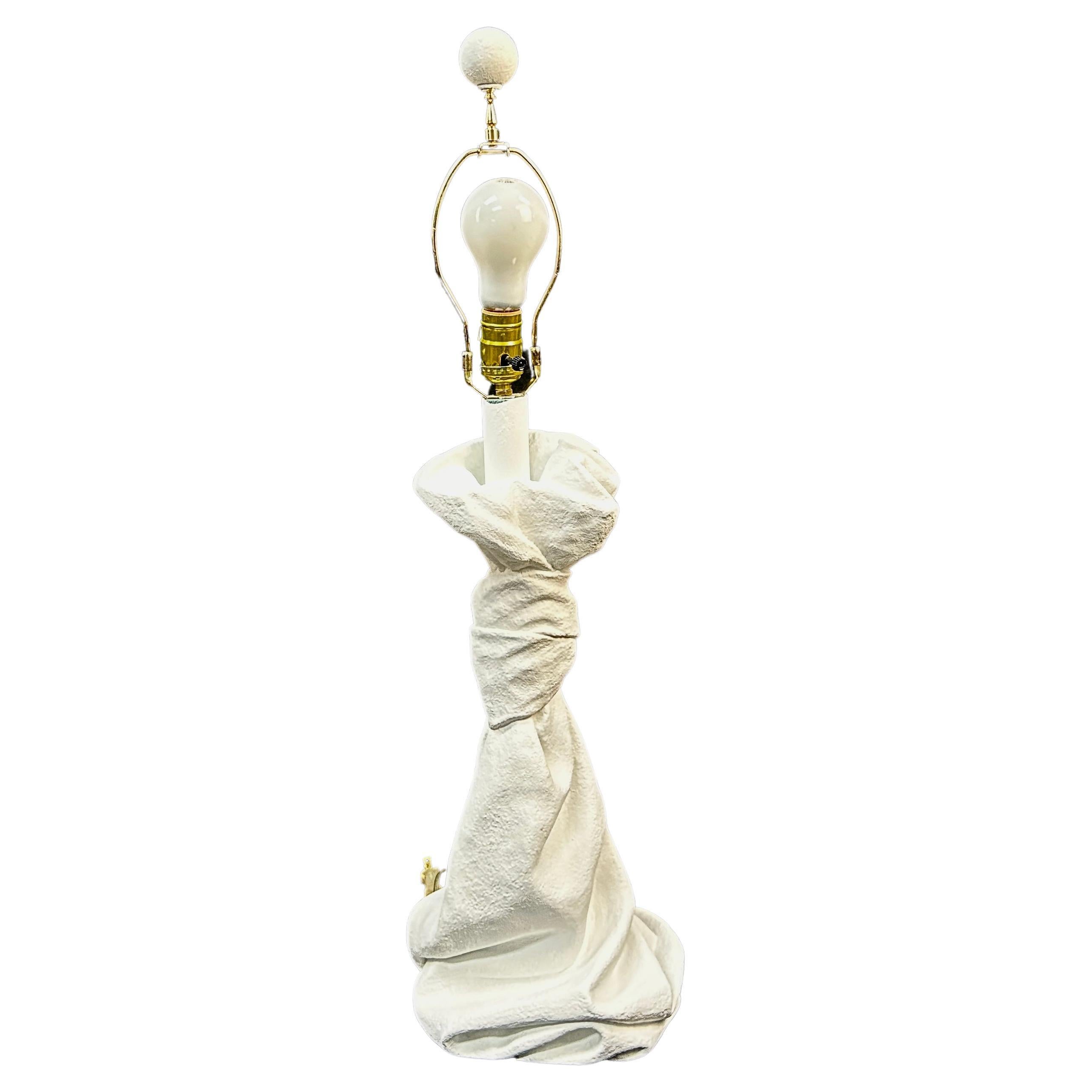 20th century plaster table lamp in the John Dickinson style of the 1970s. Draped and knotted, this unique lamp appears sculptural in design. Lamp includes the harp and the original  plaster ball finial. This heavy and sturdy lamp is in good working