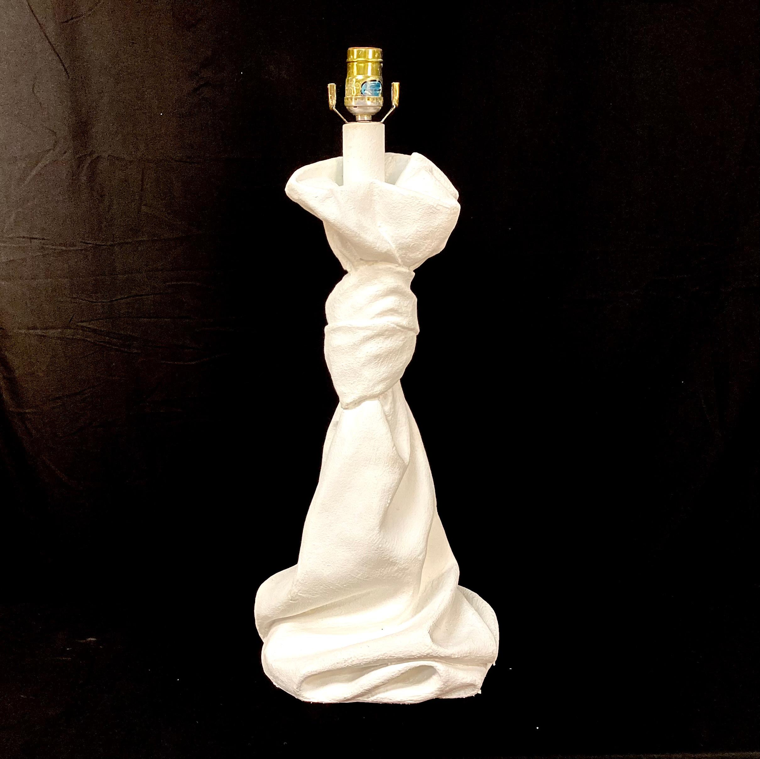 Lampe de table en plâtre du 20e siècle dans le style John Dickinson des années 1970. Drapée et nouée, cette lampe unique semble sculpturale dans son design et, avec sa forme fluide, elle rappelle un tissu ou une draperie. Cette lampe lourde et
