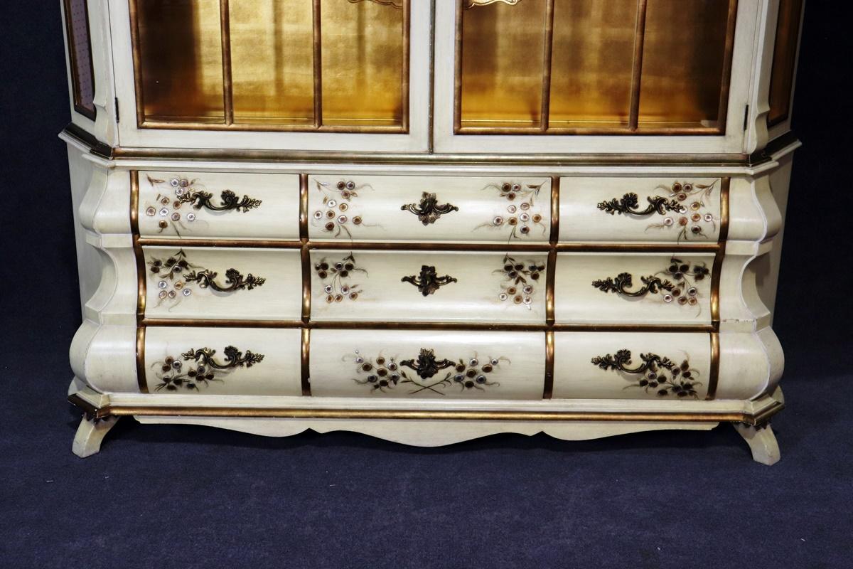 This is a special and unique breakfront China cabinet. The cabinet features a 2-piece design and can be delivered inside almost any home. The top section is replete with 24-karat gold leaf gilded surfaces and shelving and individually glazed panes