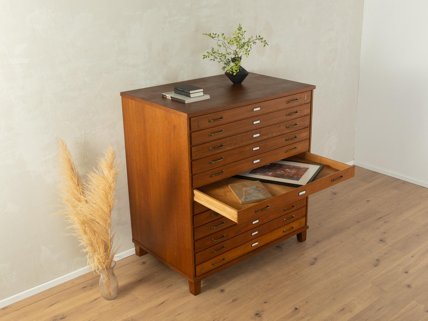 Wonderful drawer cabinet from the 1950s. High-quality corpus made of block board in dark stained ash veneer with 12 drawers and slanted feet.

Quality Features:
very good workmanship
high-quality materials
mortise & tenon solid wood drawers
Made in