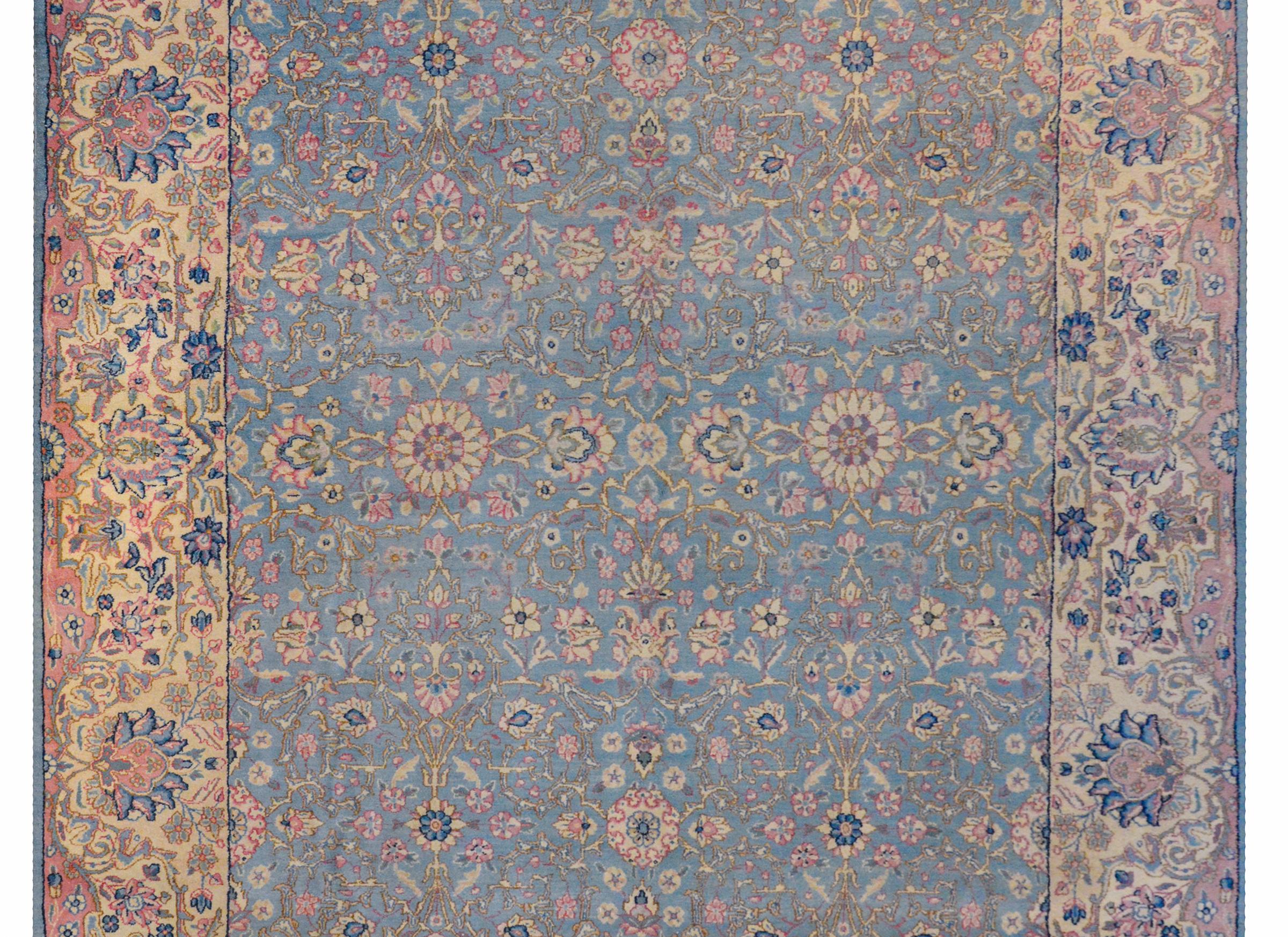 A wonderful early 20th century Persian Kirman rug with a floral lattice pattern woven in dreamy colors of pink, fuchsia, cream, and dark indigo on a light indigo background surrounded by an extraordinary wide border with a large-scale floral and