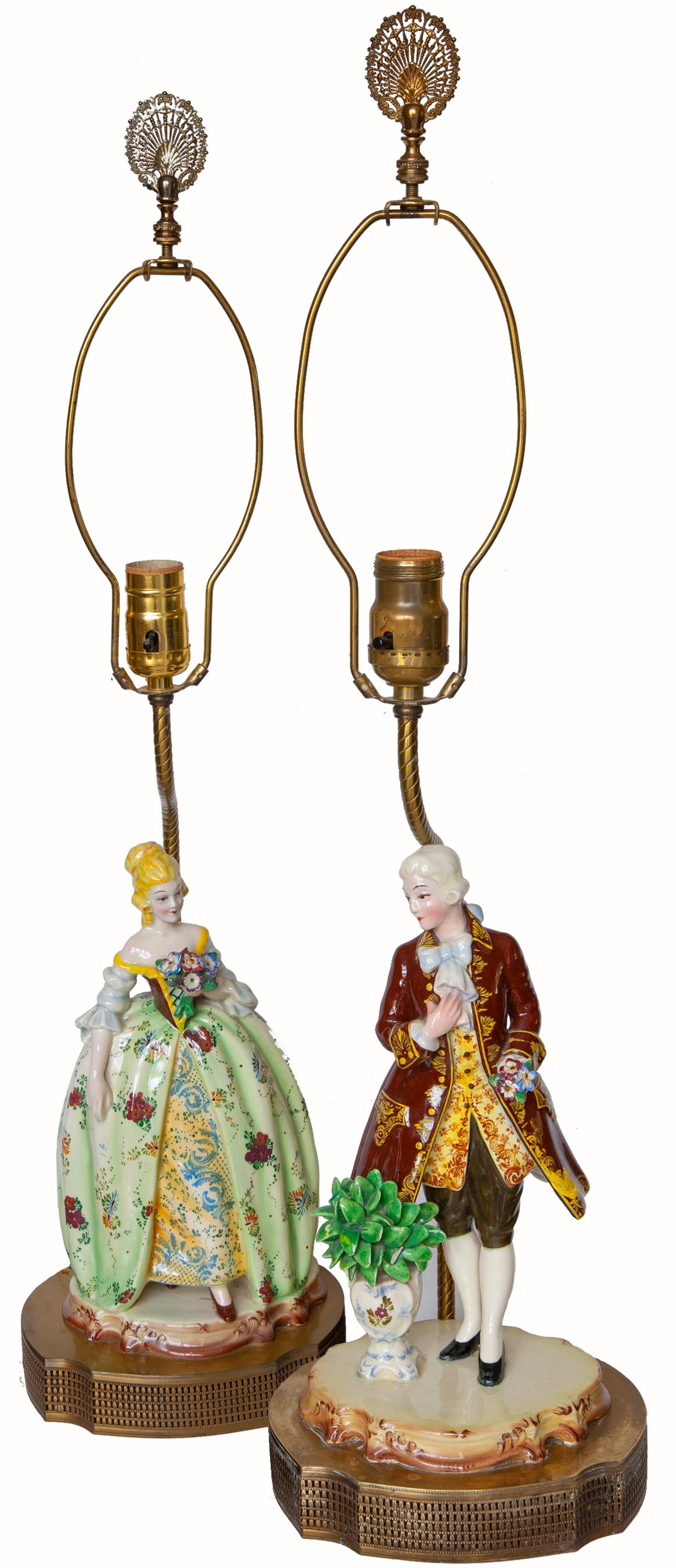 Romantic movement fine quality porcelain figurines feature Classic German attire from the late Rococo era. These figurines were fitted to pierced bases with lamp fittings around 1920-1930. Original finials & gold hardback lampshades are