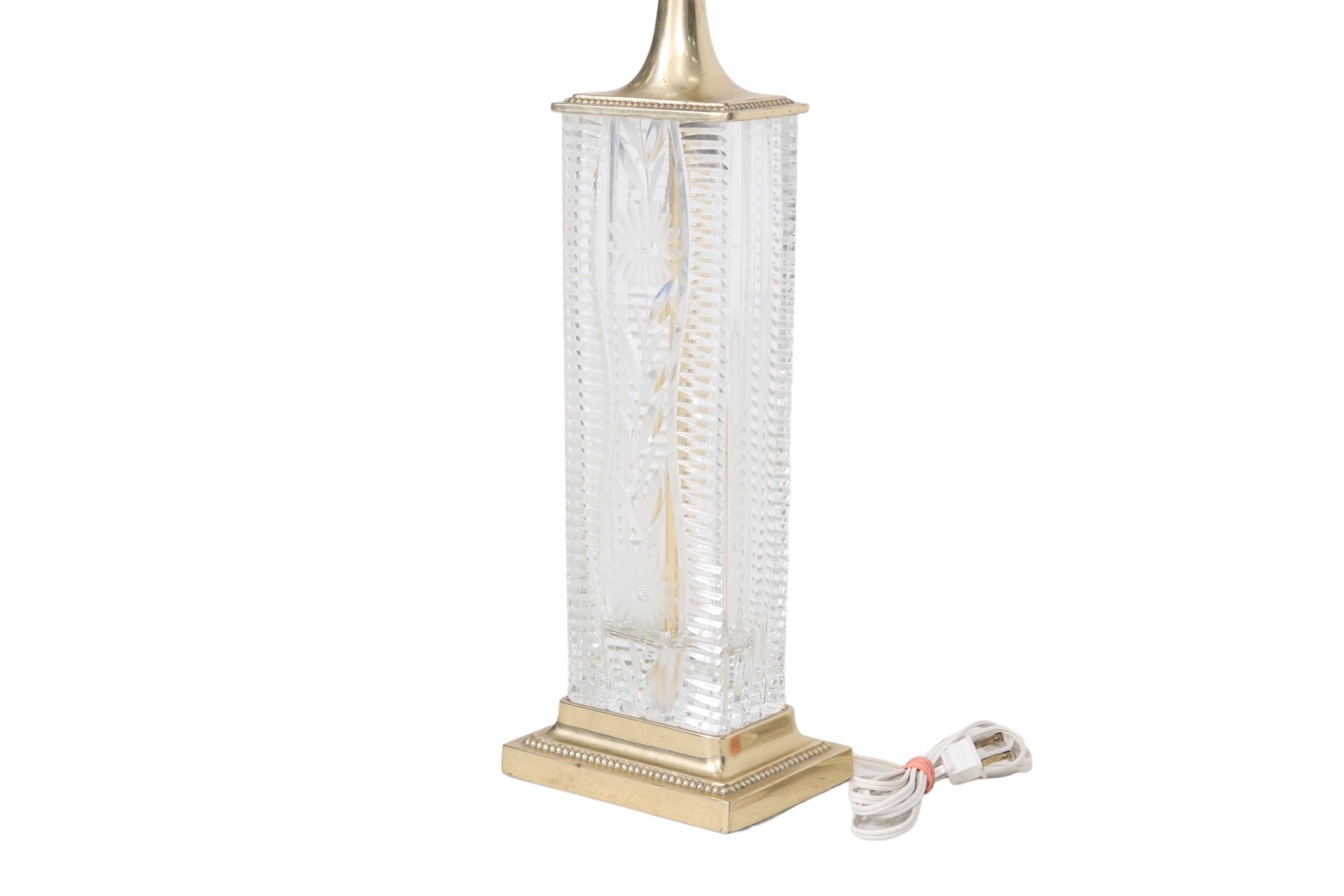 A tall, rectangular, deep cut lead crystal table lamp made by Dresden as the etched signature shows. An intricately cut flower is on the front and back, with a horizontal vesica prism pattern on each side. The rectangular top and base of the lamp