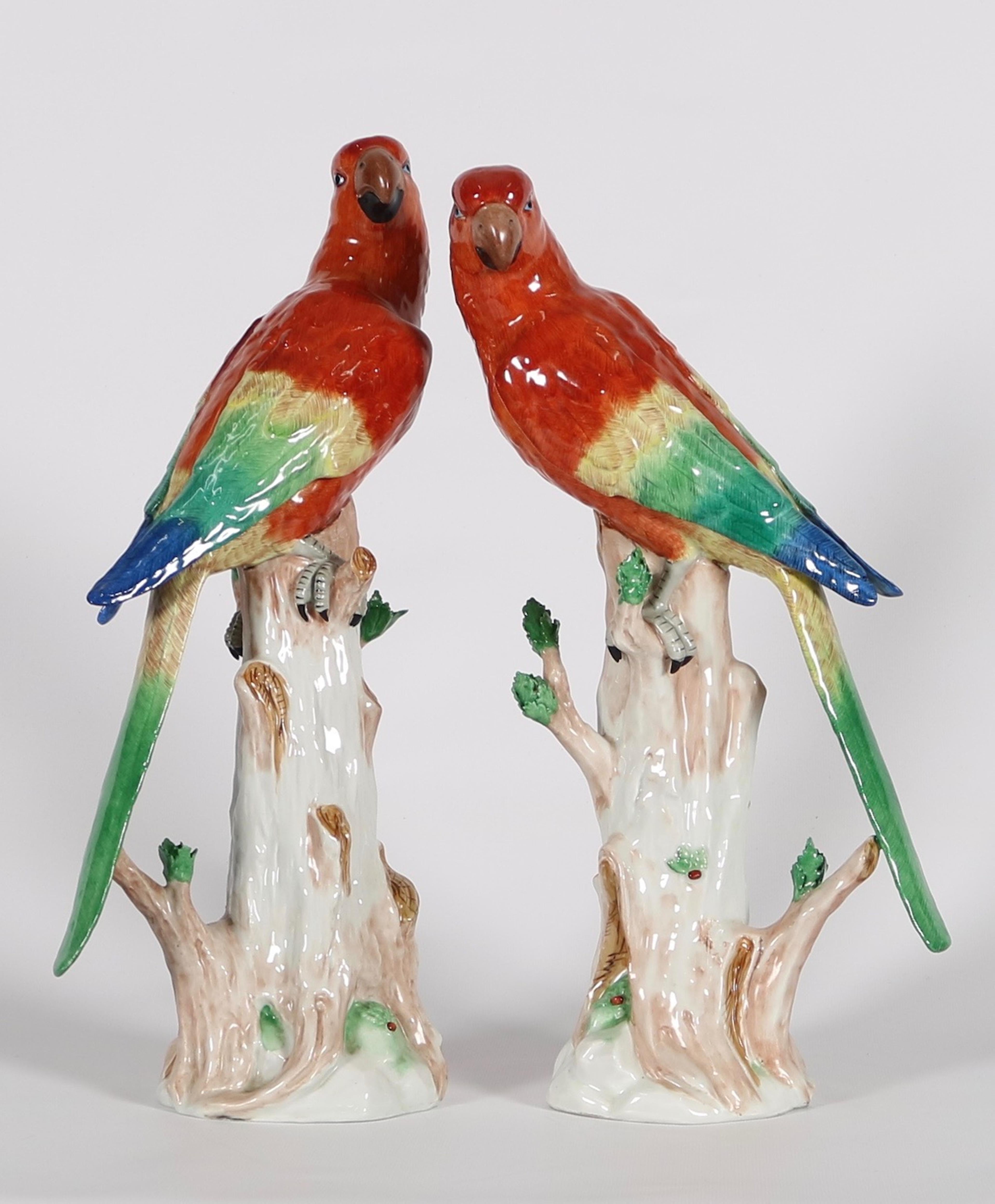 Dresden Porcelain macaw parrot sculptures. The pair are depicted seated on tree trunks with bright red plumage. Marked SP Dresden on the bottom of the base. Wear appropriate to age and use. The sculptures remain in excellent condition.