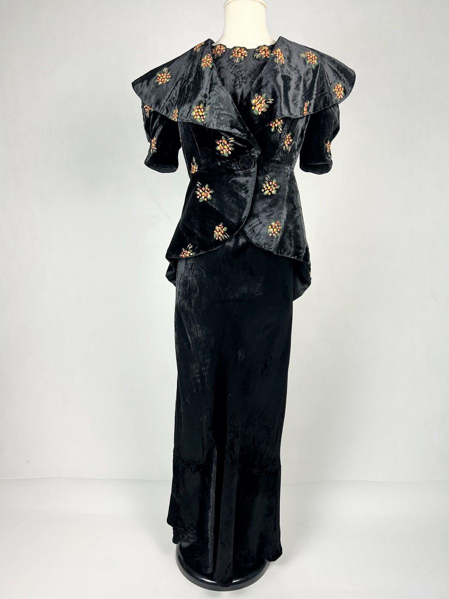 Circa 1938-1940
France
Evening dress and bolero in black silk velvet painted with floral bouquets dating from the beginning of the Second World War. Sheath dress, cut on the bias and with a large halter neckline held in place by wide straps,