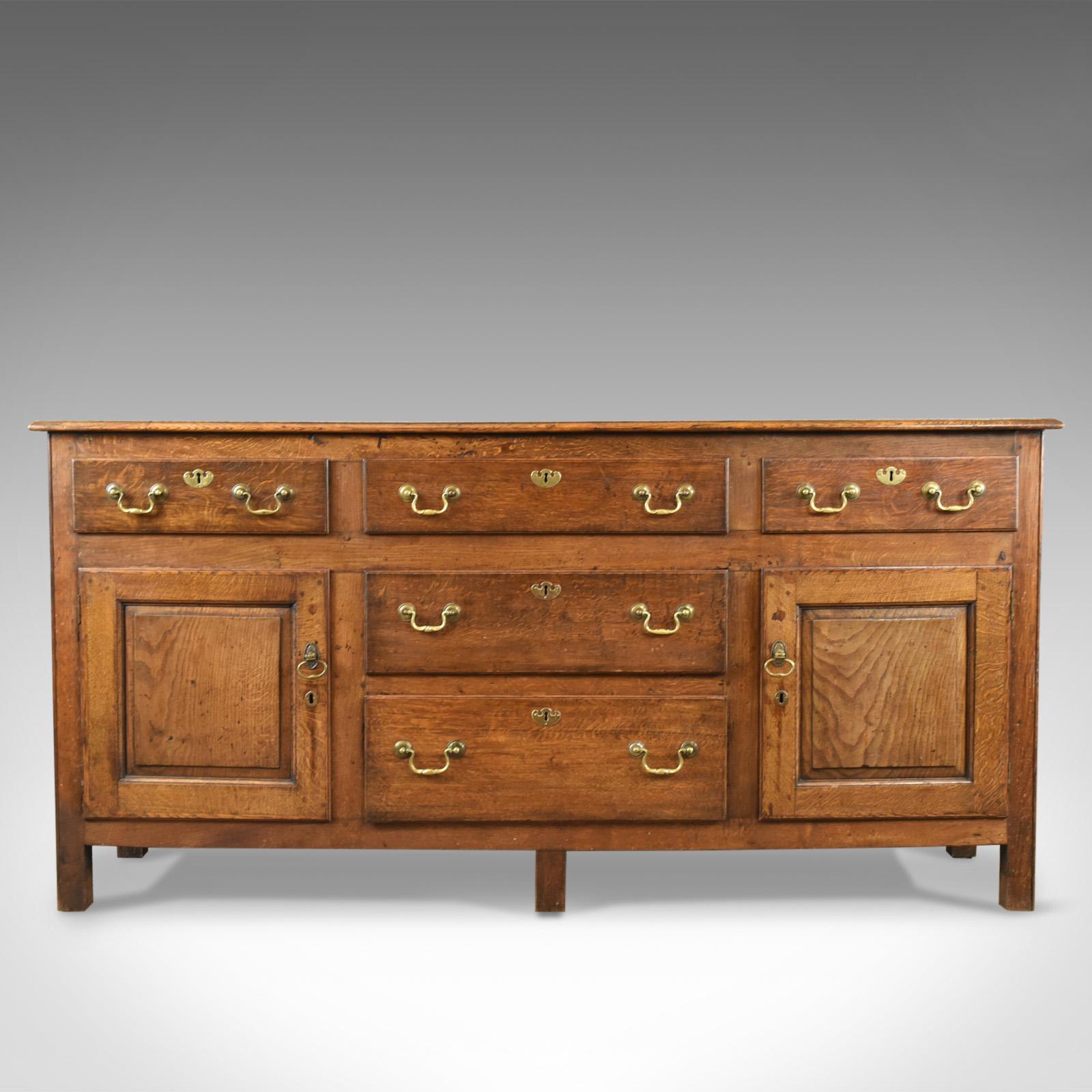 This is an antique dresser base, A Victorian, Georgian revival sideboard in English oak dating to circa 1880.

Of quality craftsmanship in stout stocks of English oak
Displaying grain interest highlighted with wisps of medullary rays
In honey