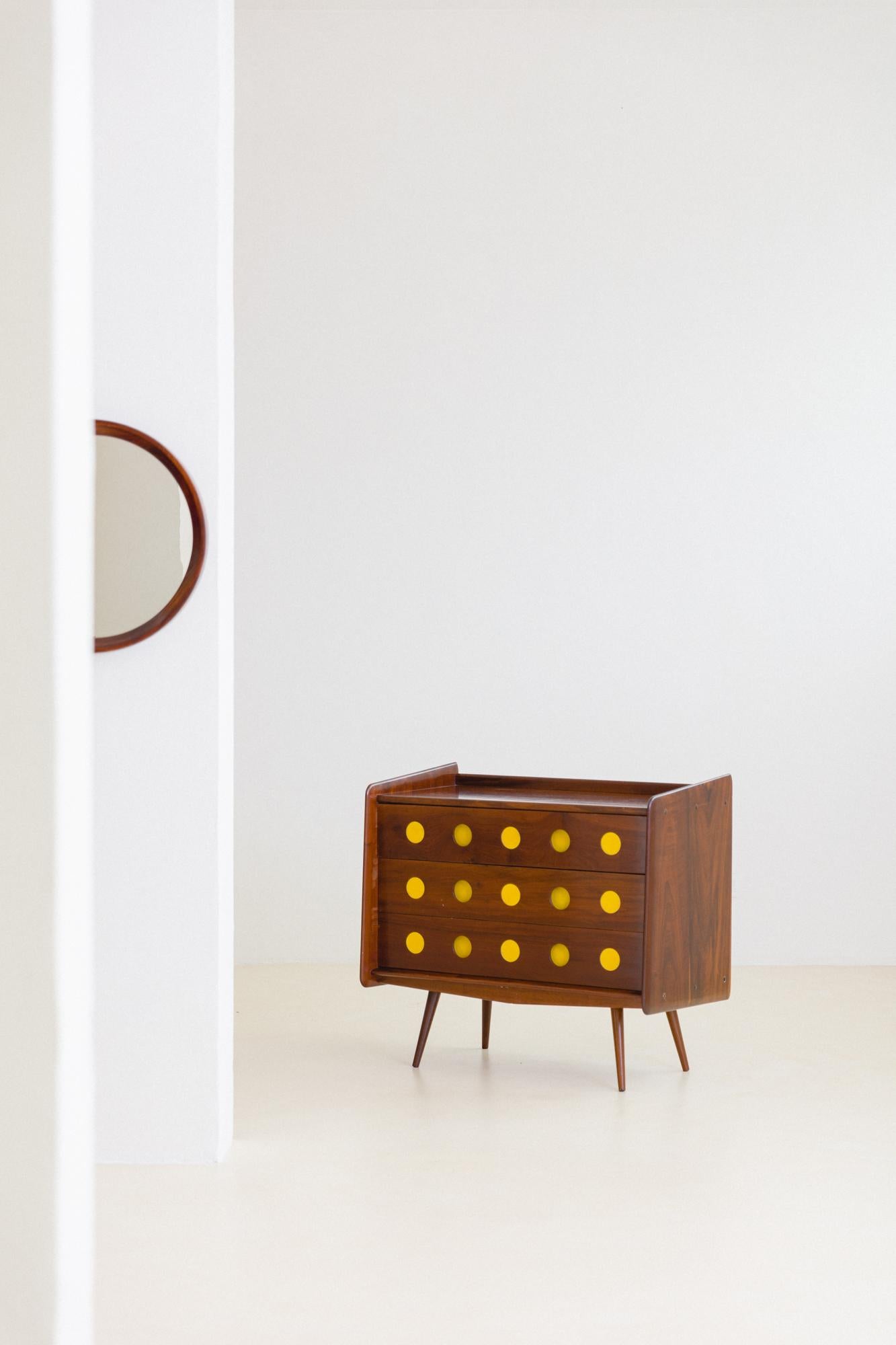 This dresser with three drawers made of solid Imbuia with details in yellow leather is an example of the ludic furniture produced by Móveis Cimo in the 1950s. Initially thought of as part of a children and youth's room collection, the dresser was
