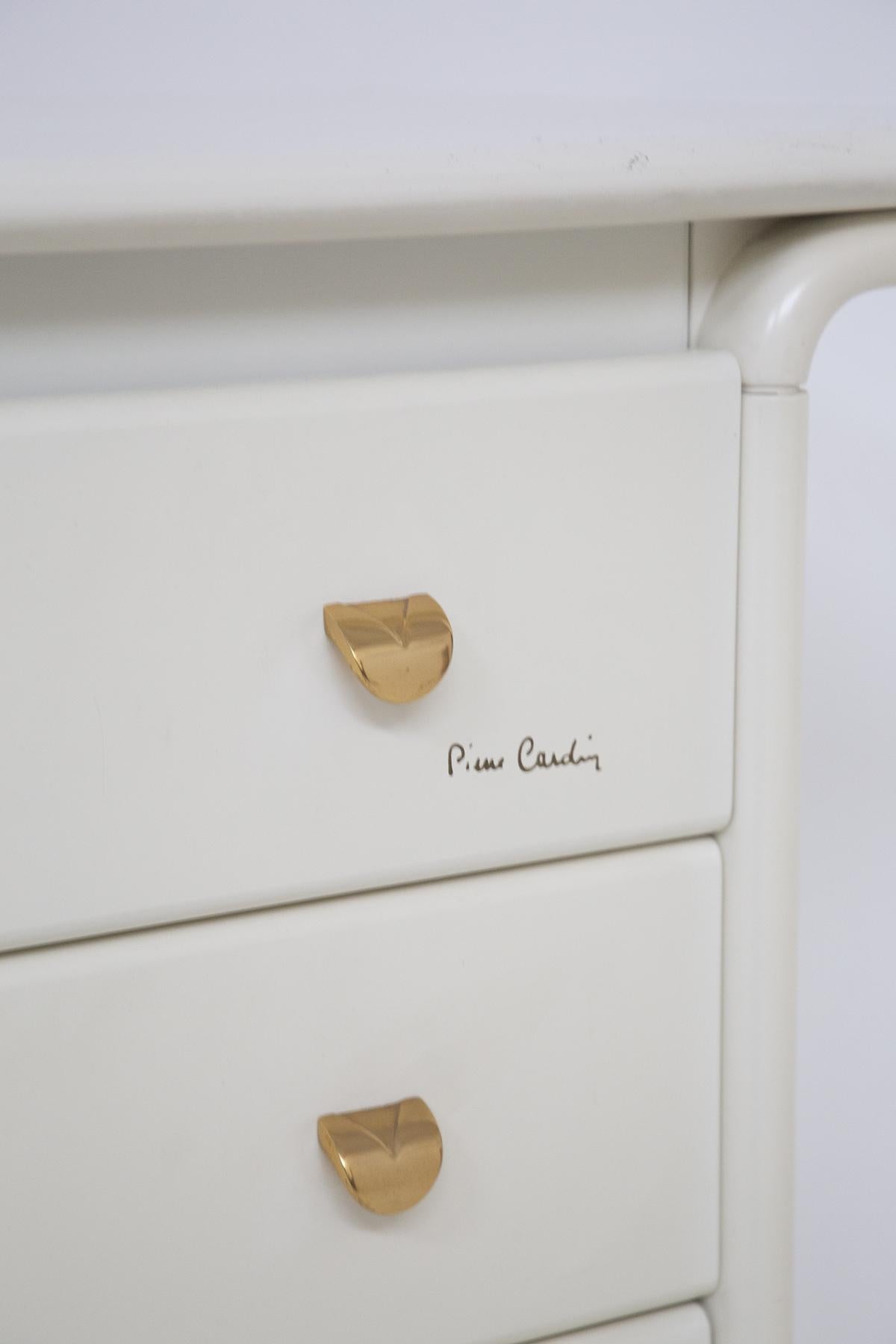 Gorgeous white wood chest of drawers designed by Pierre Cardin in the 80's, with signature.
The chest of drawers has a linear structure, made of glossy white lacquered wood.
The top of the chest of drawers ends in two semi curly that go to lighten