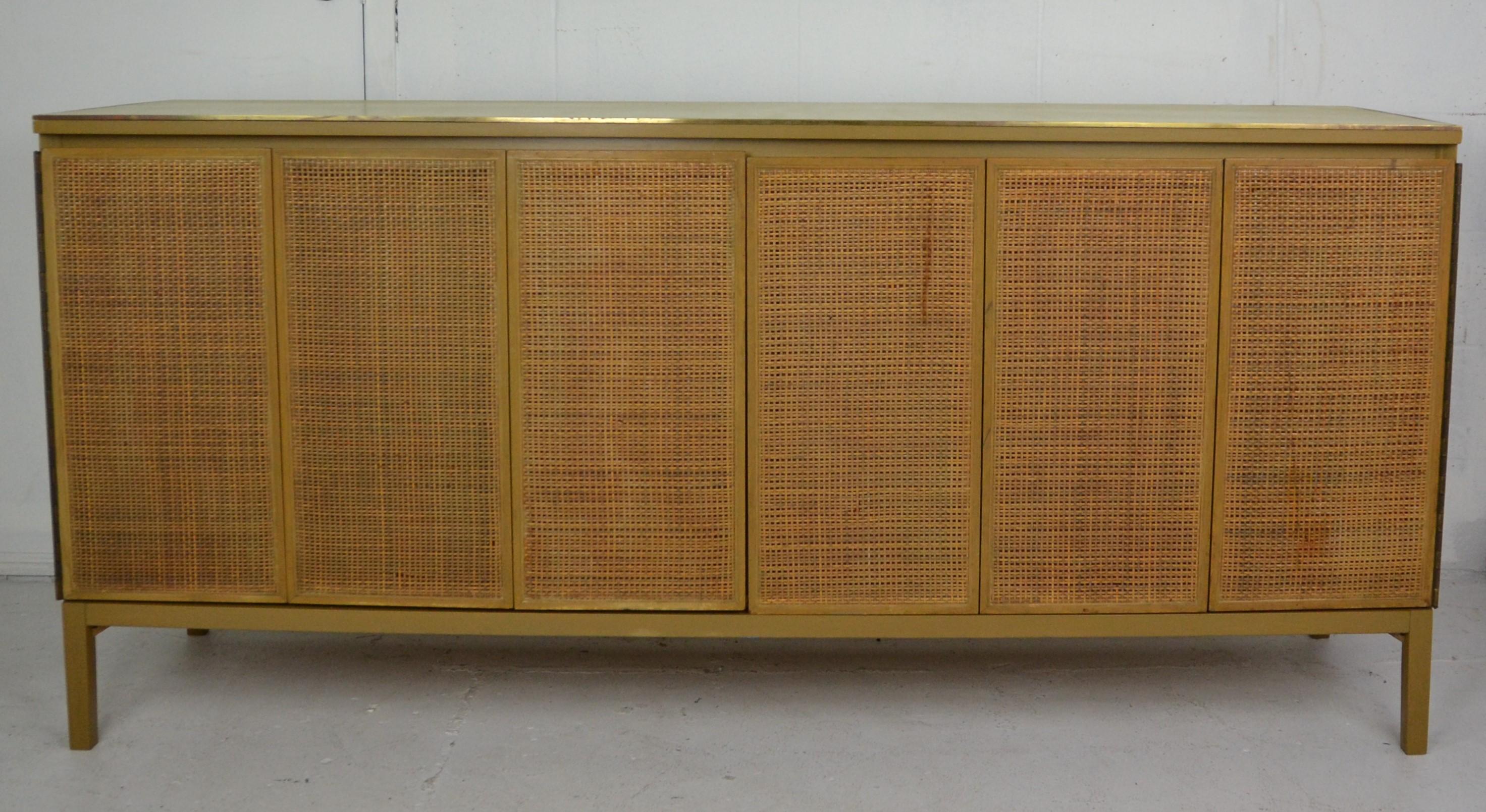 Dresser or credenza by Paul McCobb with original leather top, brass edge, cane front panels, and 8 drawers.