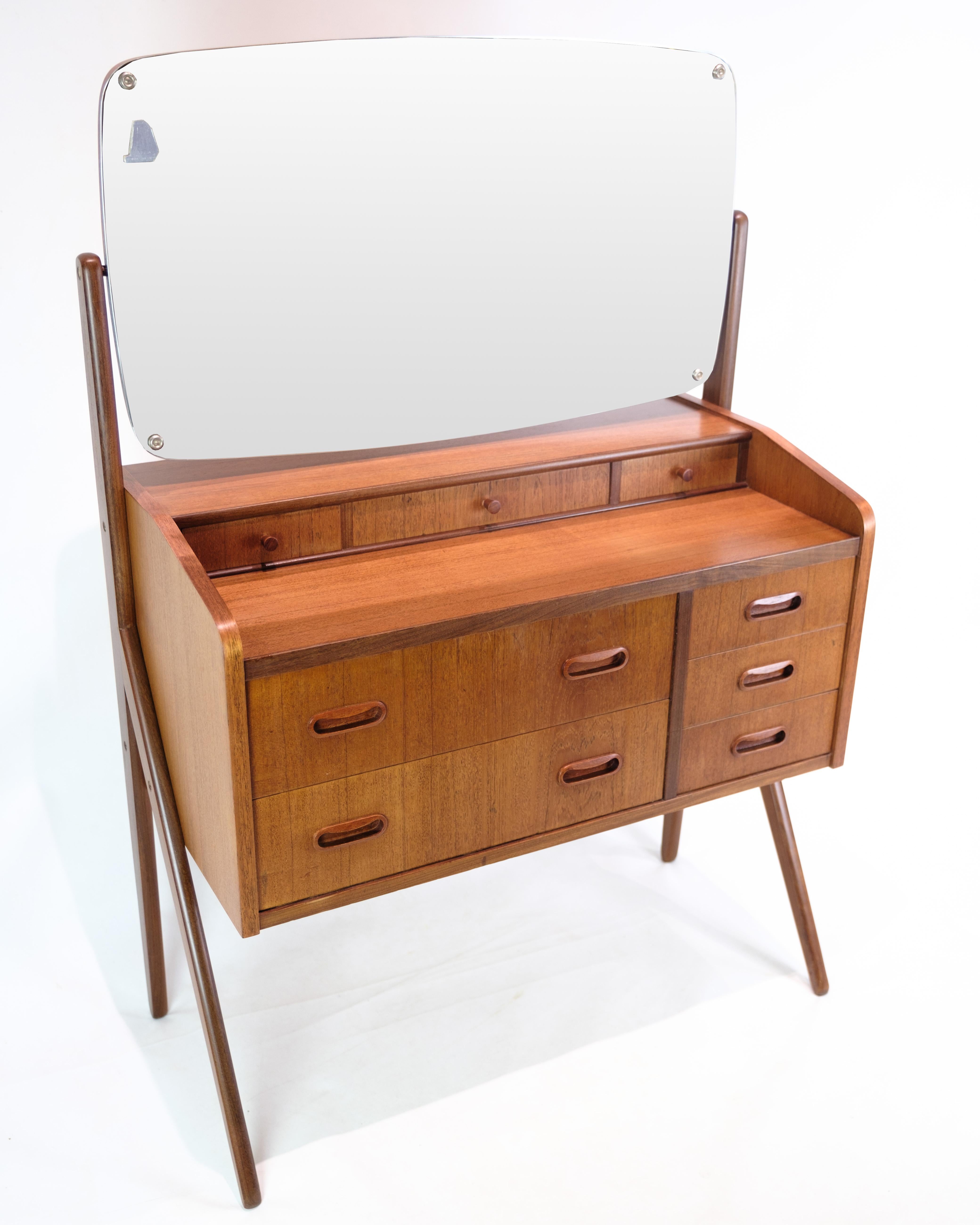 This dresser with adjustable mirror is a beautiful example of Danish design from the 1960s. Made of teak wood, it exudes the warmth and natural beauty that characterizes this popular wood material. With two large drawers and three smaller drawers,
