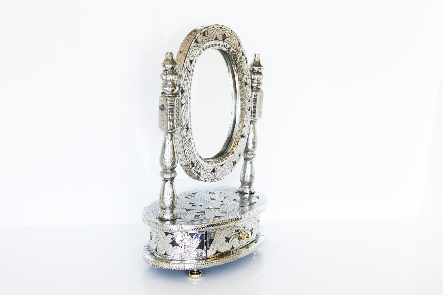 Dressing mirror with drawer, with engraved metal overlays and floral arabesque patterns covering the entirety. The drawer’s knob and feet are cast brass.
