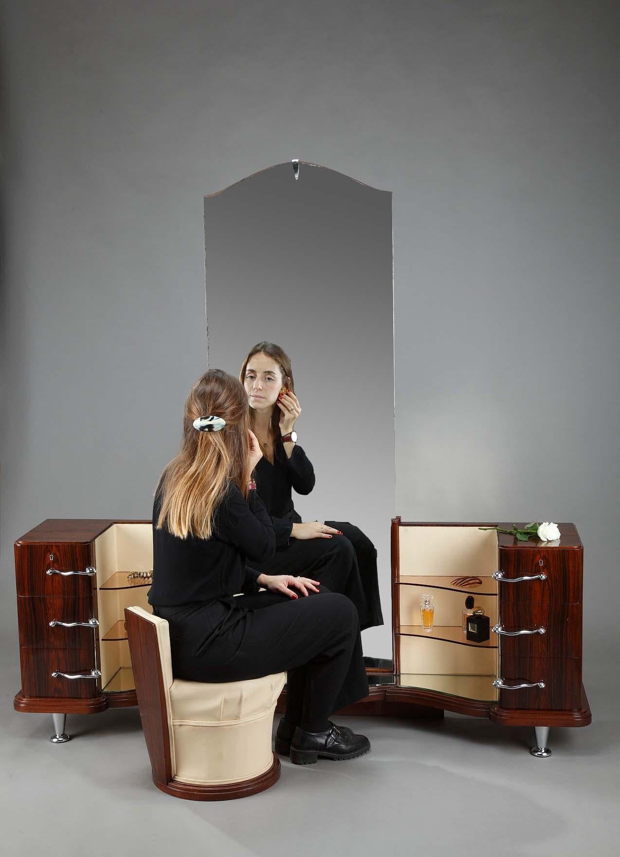 Beautiful Art Deco dressing table and its small chair in Macassar ebony veneer by the decorator Claude de Plasse. In the center, a large mirror is surrounded by two lateral storage units, each composed of three drawers opening with curved chrome