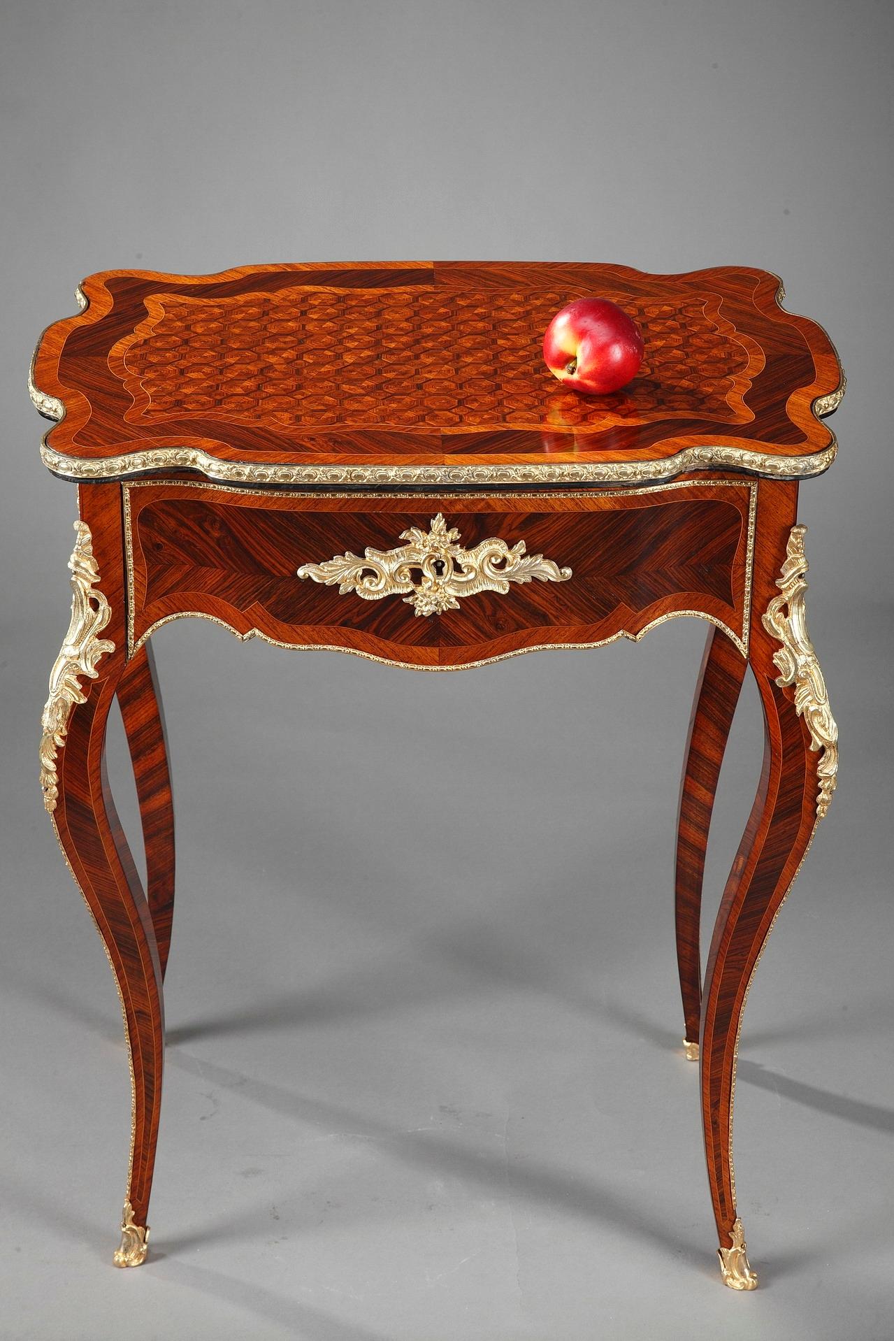 Napoleon III antique dressing table in exotic wood veneers, with flowing lines accented by fine cast bronze ormolu decoration of ova, rinceau and scrolls. The tabletop adorned with wood marquetry opens up over a storage compartment and a drawer
