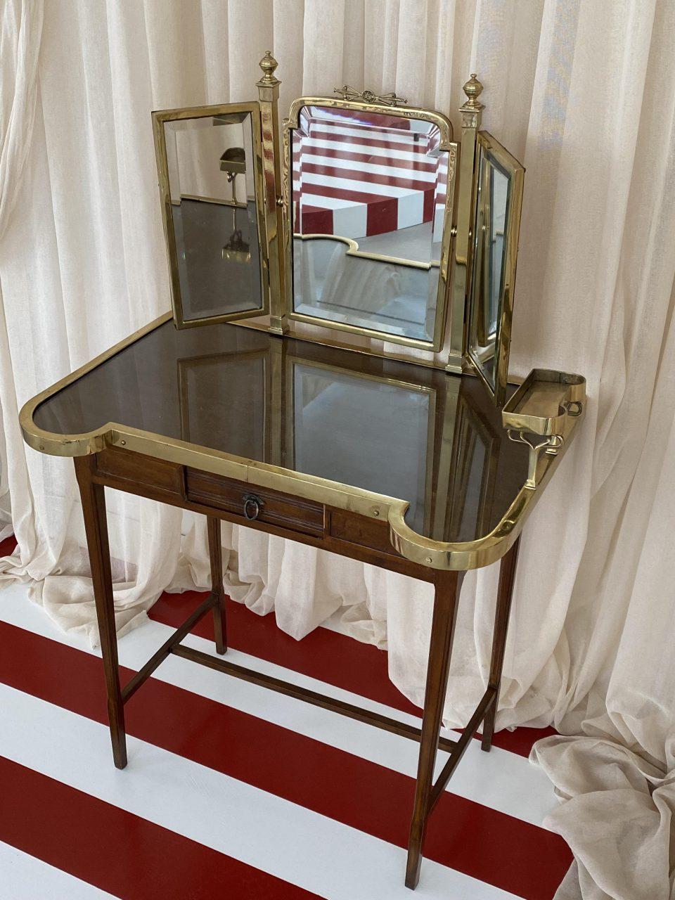 Sit down at this sophisticated dressing table / vanity, and live out your innermost princess dream.

Stylish, and extremely elegant 1920s French dressing table, in a gorgeous design, with a beautiful slim dark wood base and a 3-panelled brass