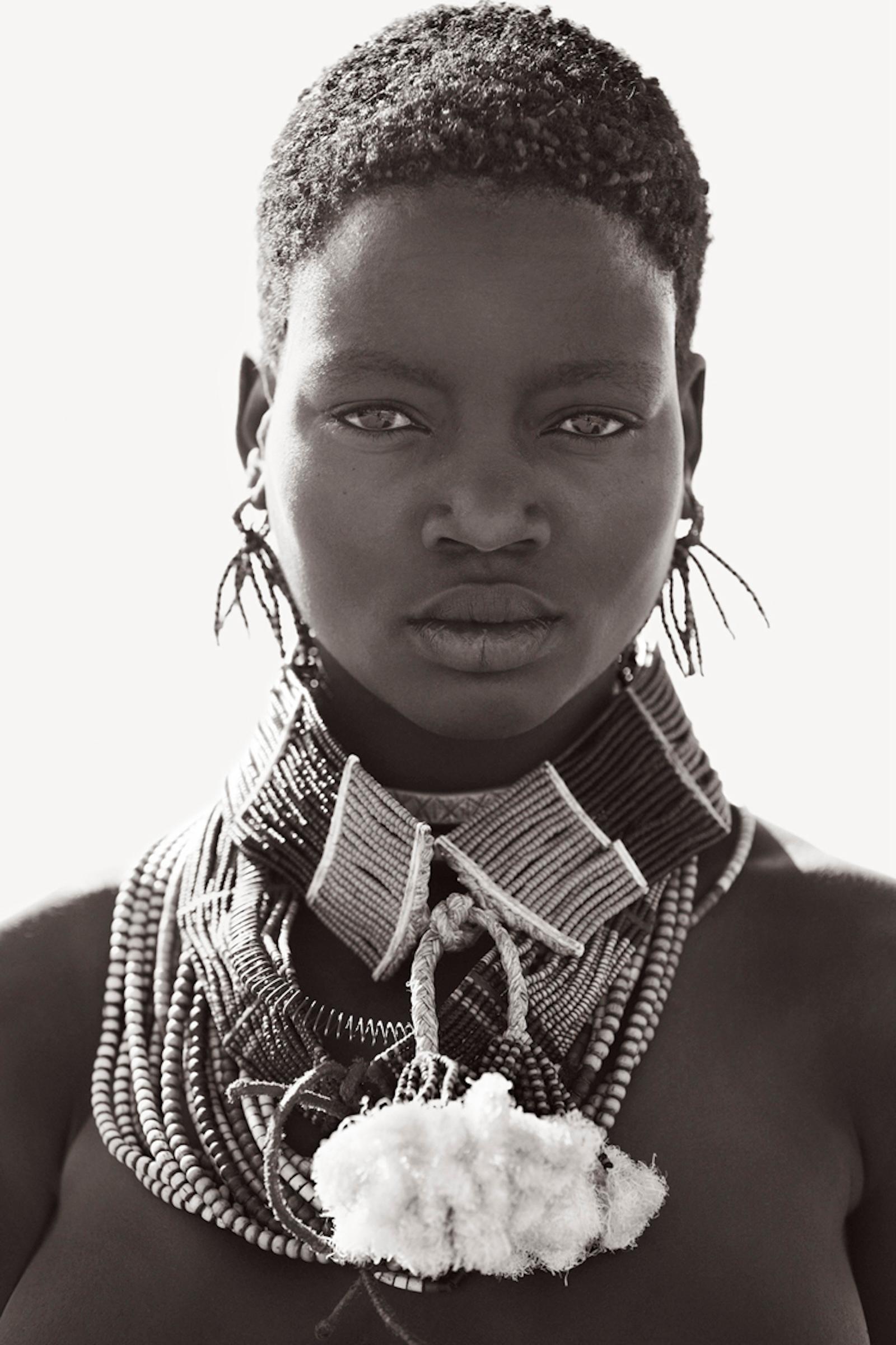 Una mujer Hamar con adornos tradicionales sobre un fondo de luz - Photograph de Drew Doggett