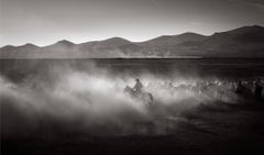 A lone cowboy emerges through the dust in this black and white print