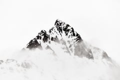 A lone snowy peak rising above the clouds and mist with a flat white minimal nat