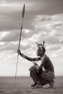 A Rendille warrior crouching on the ground with his spear in hand in the desert