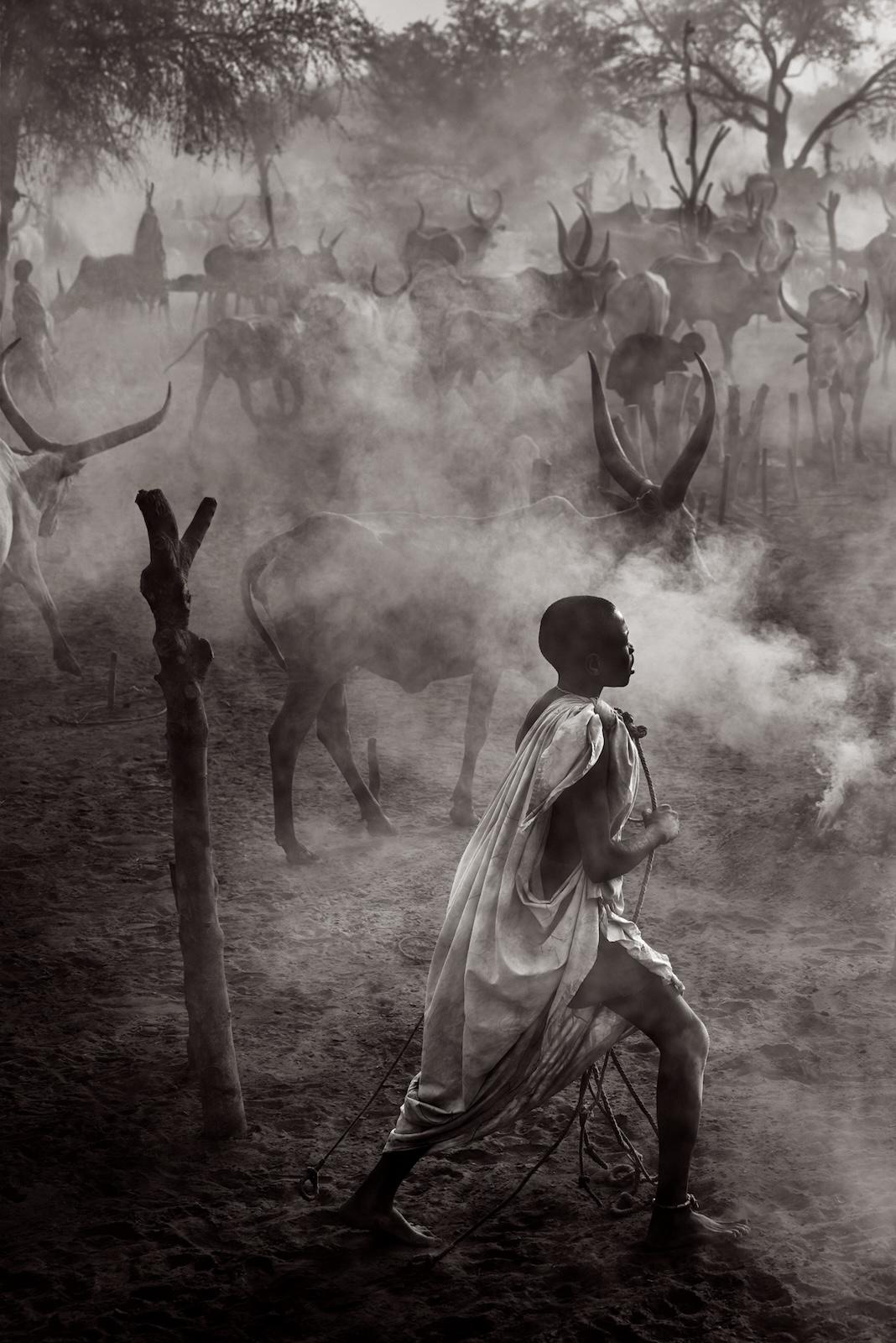 Un jeune Mundari marche dans les camps de bétail enfumés et poussiéreux du Sud-Soudan.