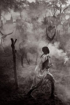 A young Mundari man walks through the smoky, dusty cattle camps of South Sudan