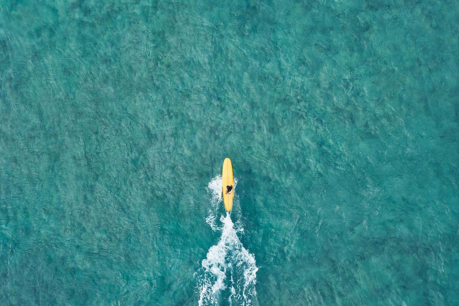 Immagine aerea di un surfista su una tavola gialla - Photograph di Drew Doggett