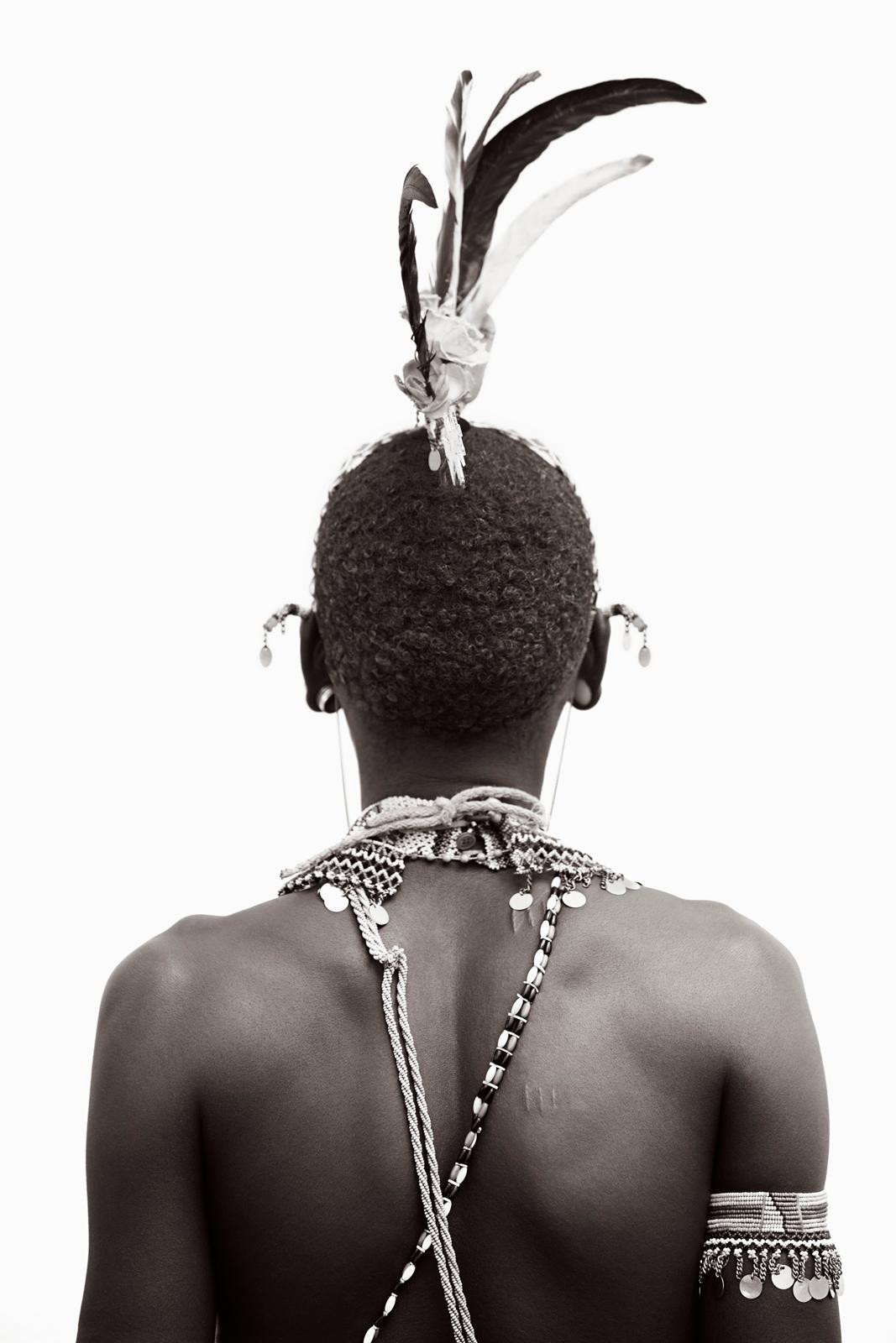 Drew Doggett Black and White Photograph - Black and white portrait of the back of a young Rendille warrior wearing traditi