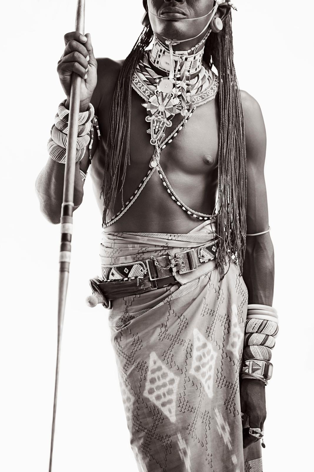 Portrait en noir et blanc de face d'un jeune guerrier Samburu tenant une lance. - Photograph de Drew Doggett