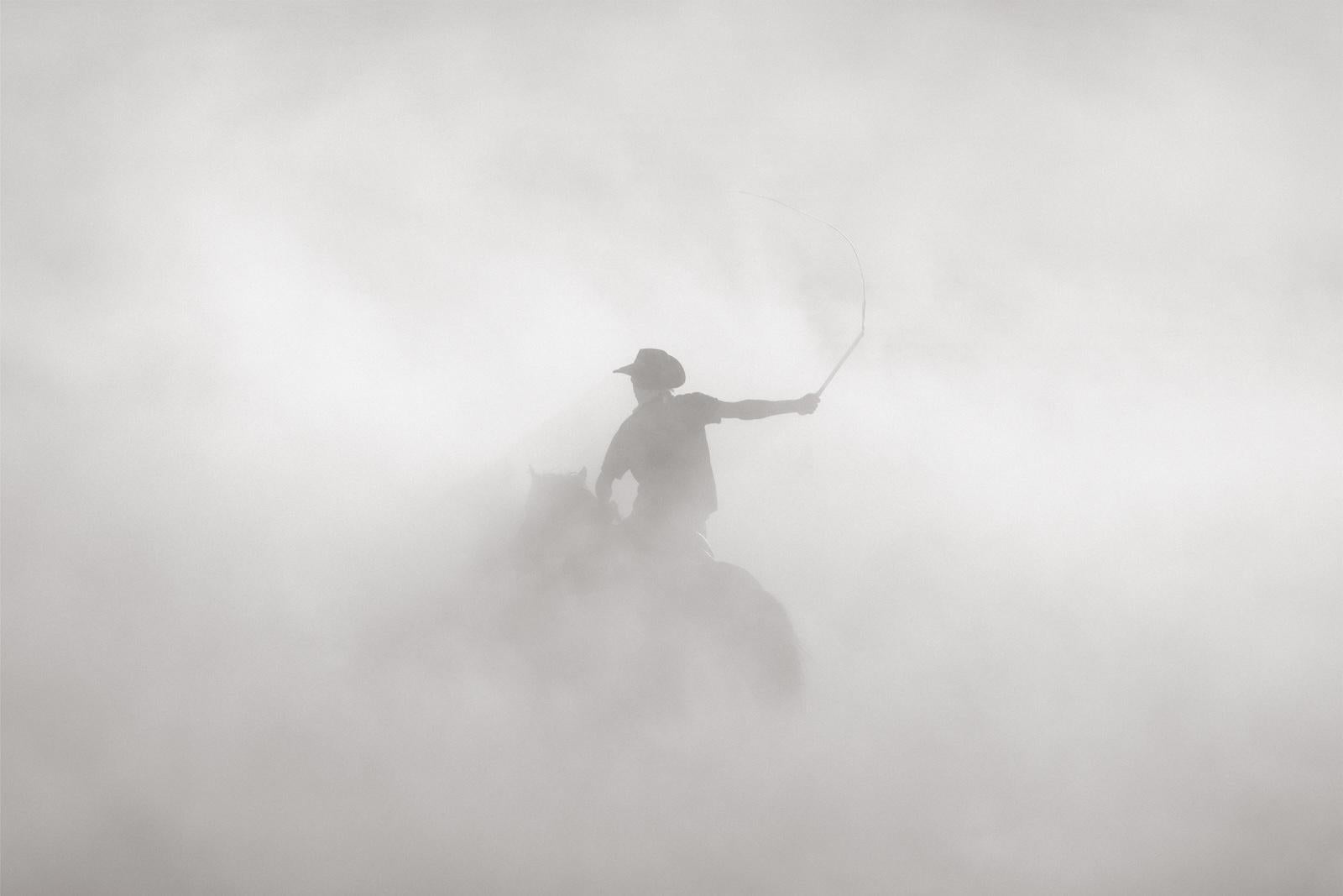 Cowboy sul suo cavallo che si alza sopra la polvere in un momento etereo - Photograph di Drew Doggett
