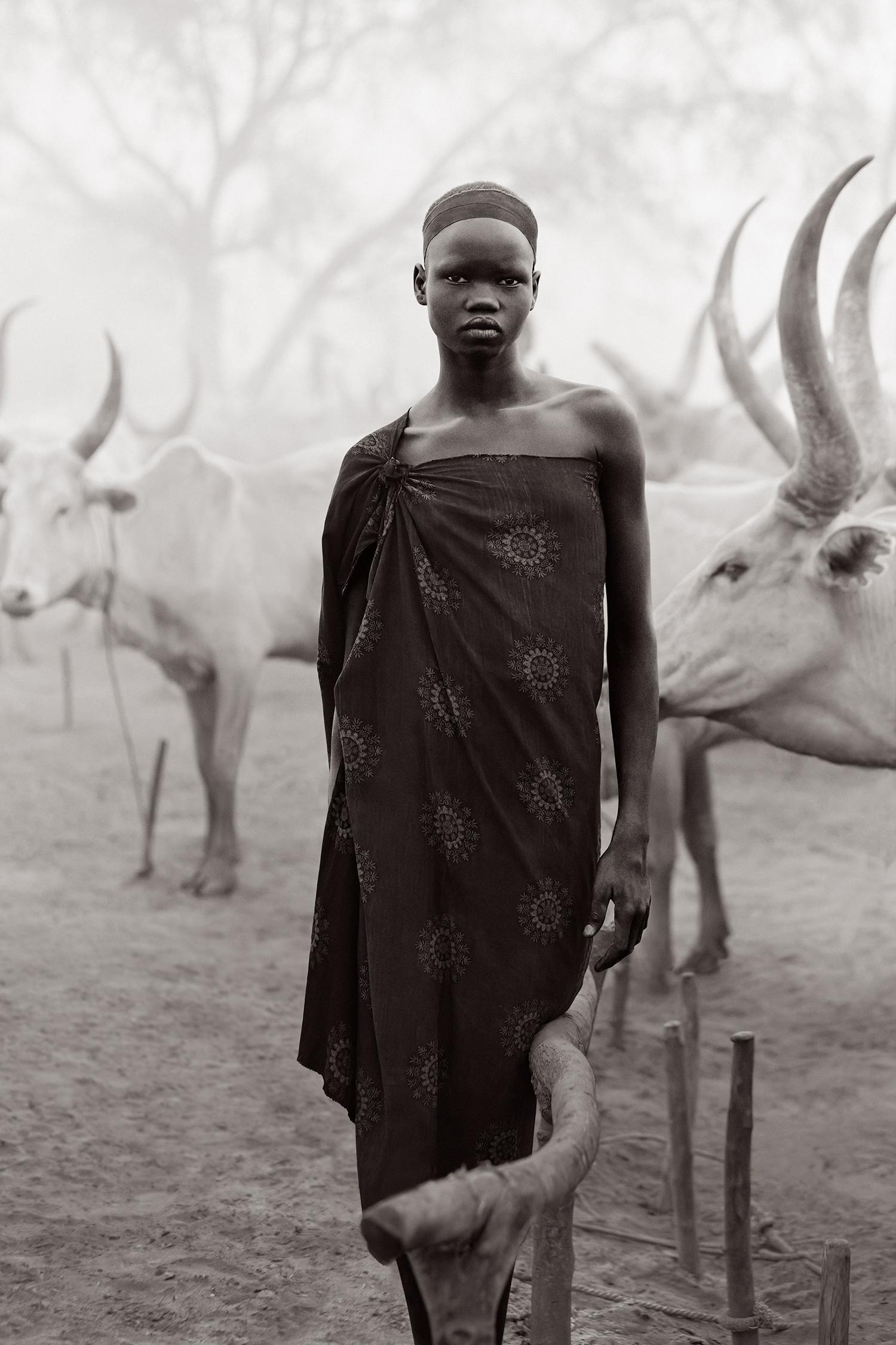 Drew Doggett Black and White Photograph – Cultural Portrait eines jungen Jungen im Südsudan inmitten der Mundari- Rinderlager
