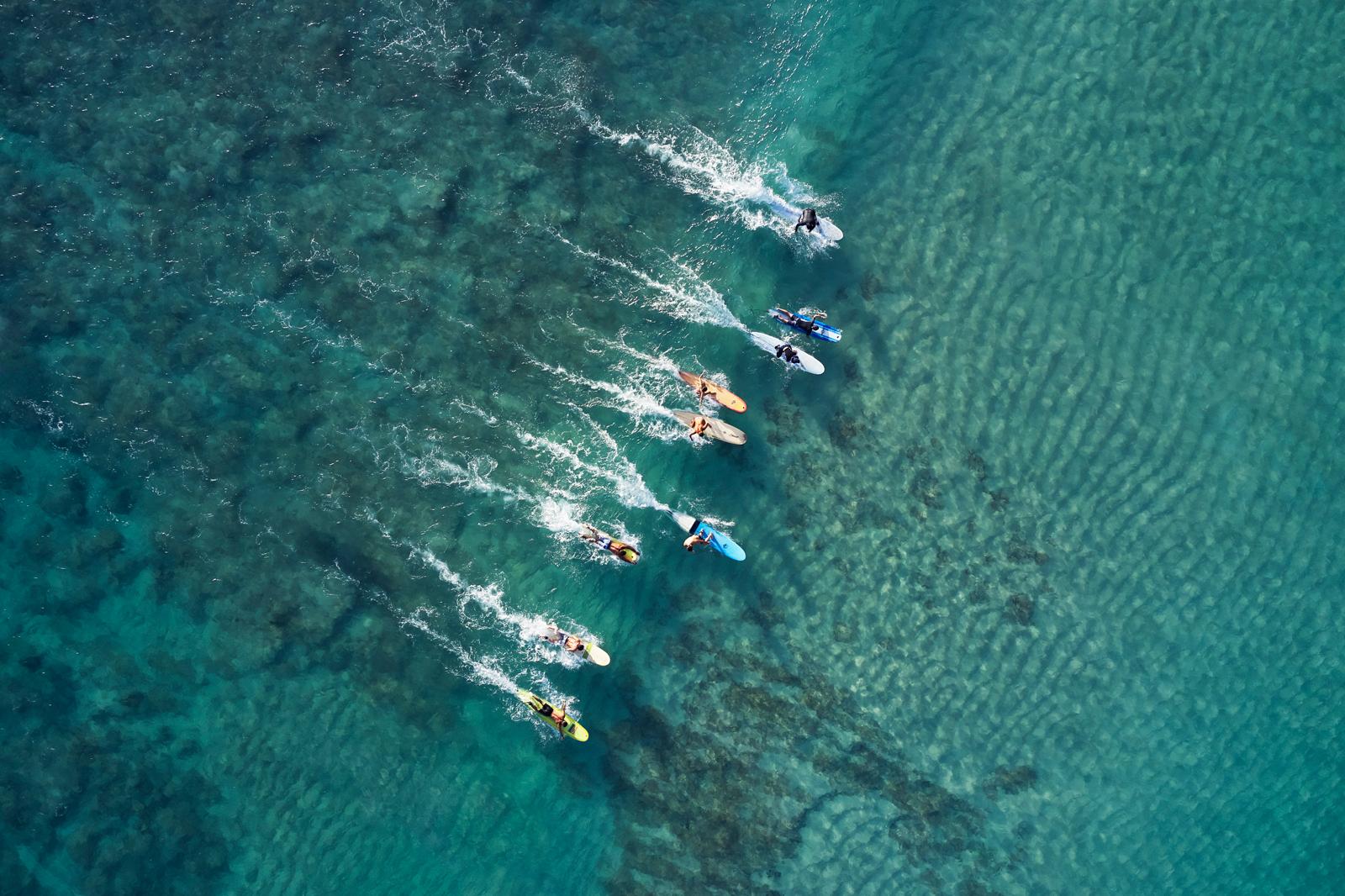 Inspirador retrato de longboarders compitiendo por coger la misma ola - Photograph de Drew Doggett