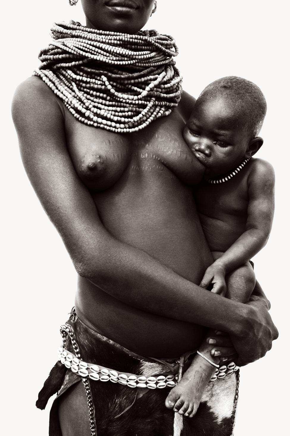 Drew Doggett Portrait Photograph - Mother Nursing Her Child, Wearing Traditional Tribal Jewelry, Ethiopia, Calming