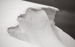 Otherworldly photograph of four penguins walking on the edge of a snowy iceberg