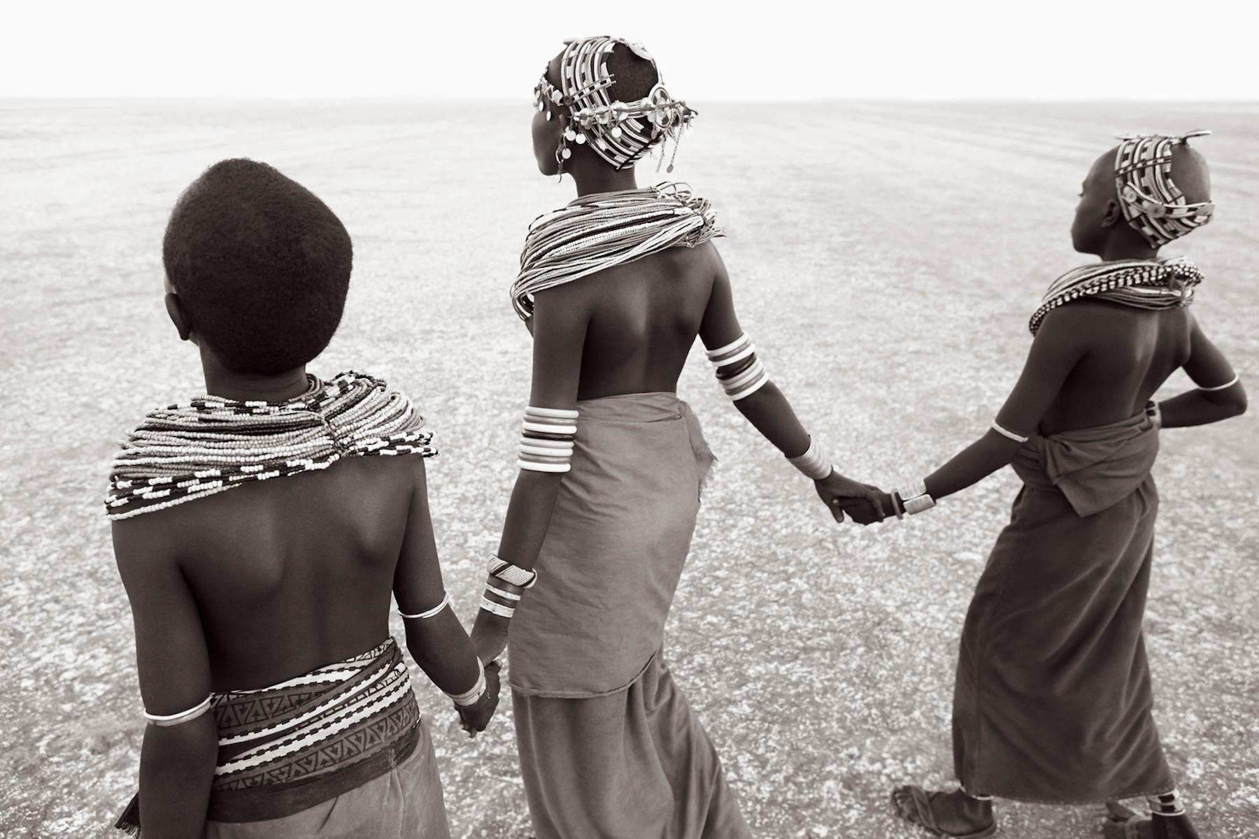 Starkes, ikonisches Bild von drei jungen Frauen, die über die Salzwiesen laufen – Photograph von Drew Doggett