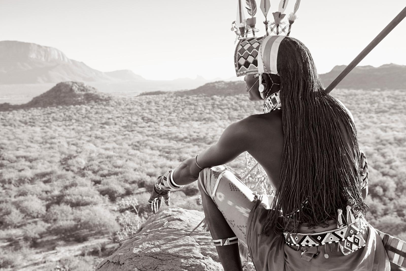 Samburu warrior sitting on a ledge overlooking his tribe's homeland - Photograph by Drew Doggett