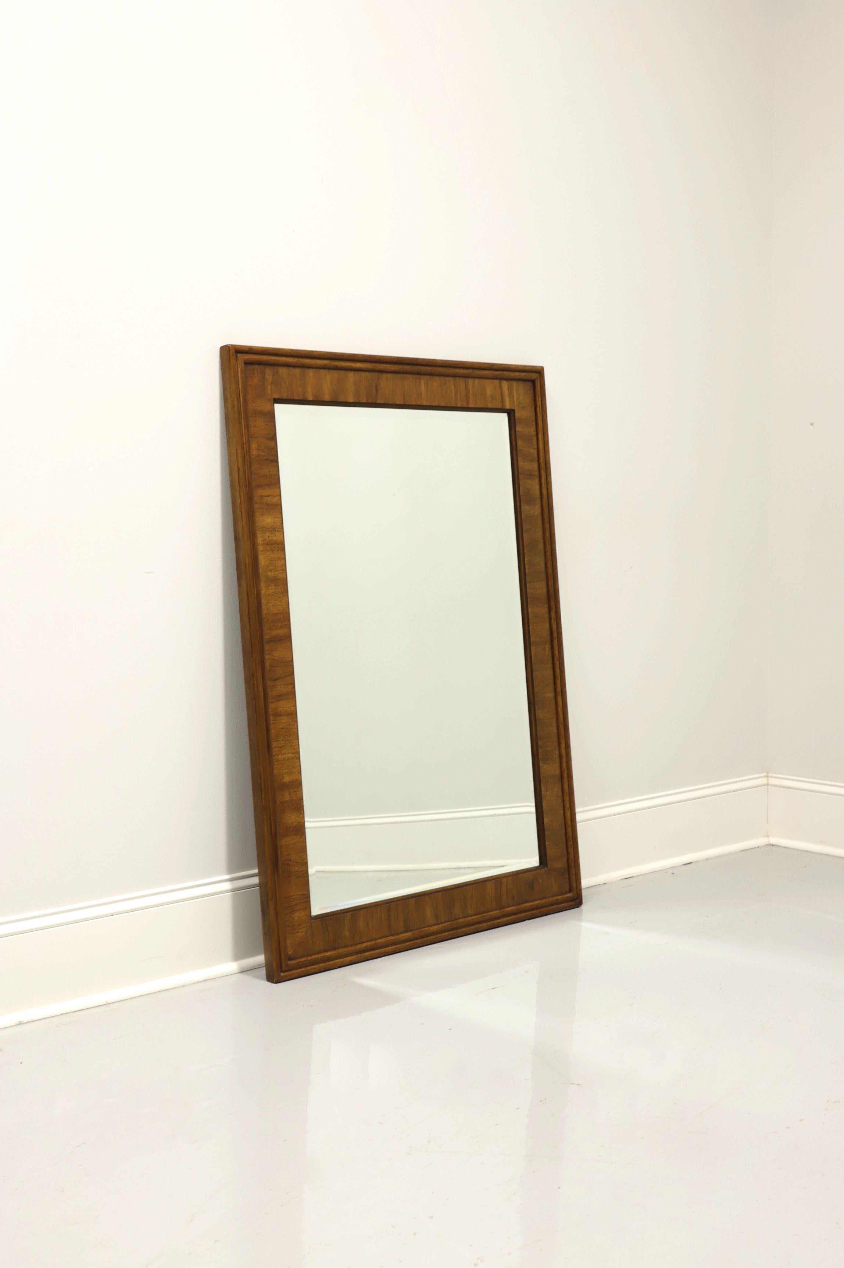 A Campaign style wall mirror by Drexel Heritage, from their Accolade collection. Beveled mirror glass and rectangular banded pecan frame. Made in North Carolina, USA, circa 1985. 

Style #: 904-212-2

Measures: 33.75 W 1.25 D 47.75 H, Weighs