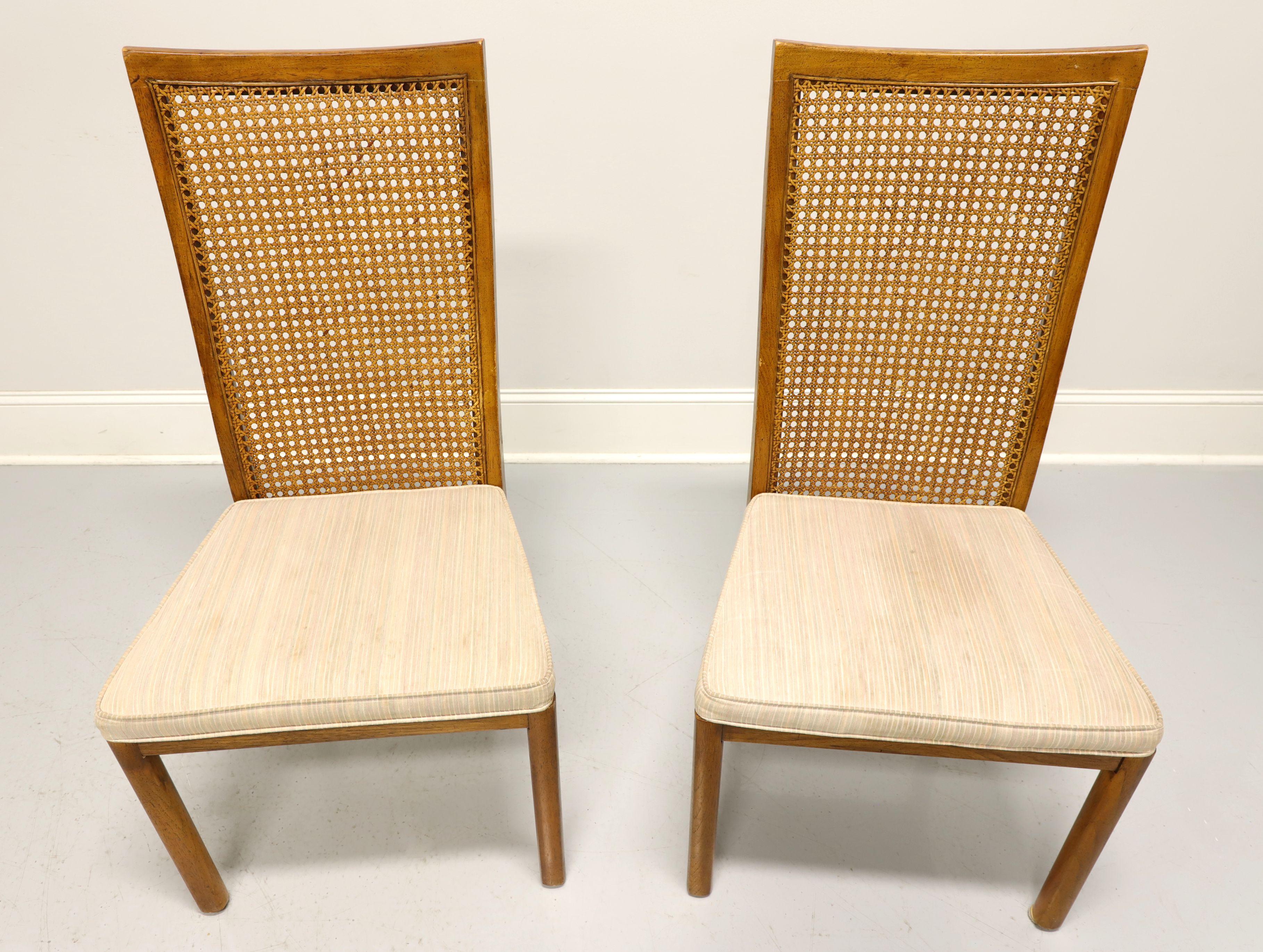 A pair of campaign style dining side chairs by Drexel Heritage, from their Accolade Collection. Pecan with a golden finish, high caned back, neutral color fabric upholstered seat and straight front legs. Made in North Carolina, USA, in the late 20th