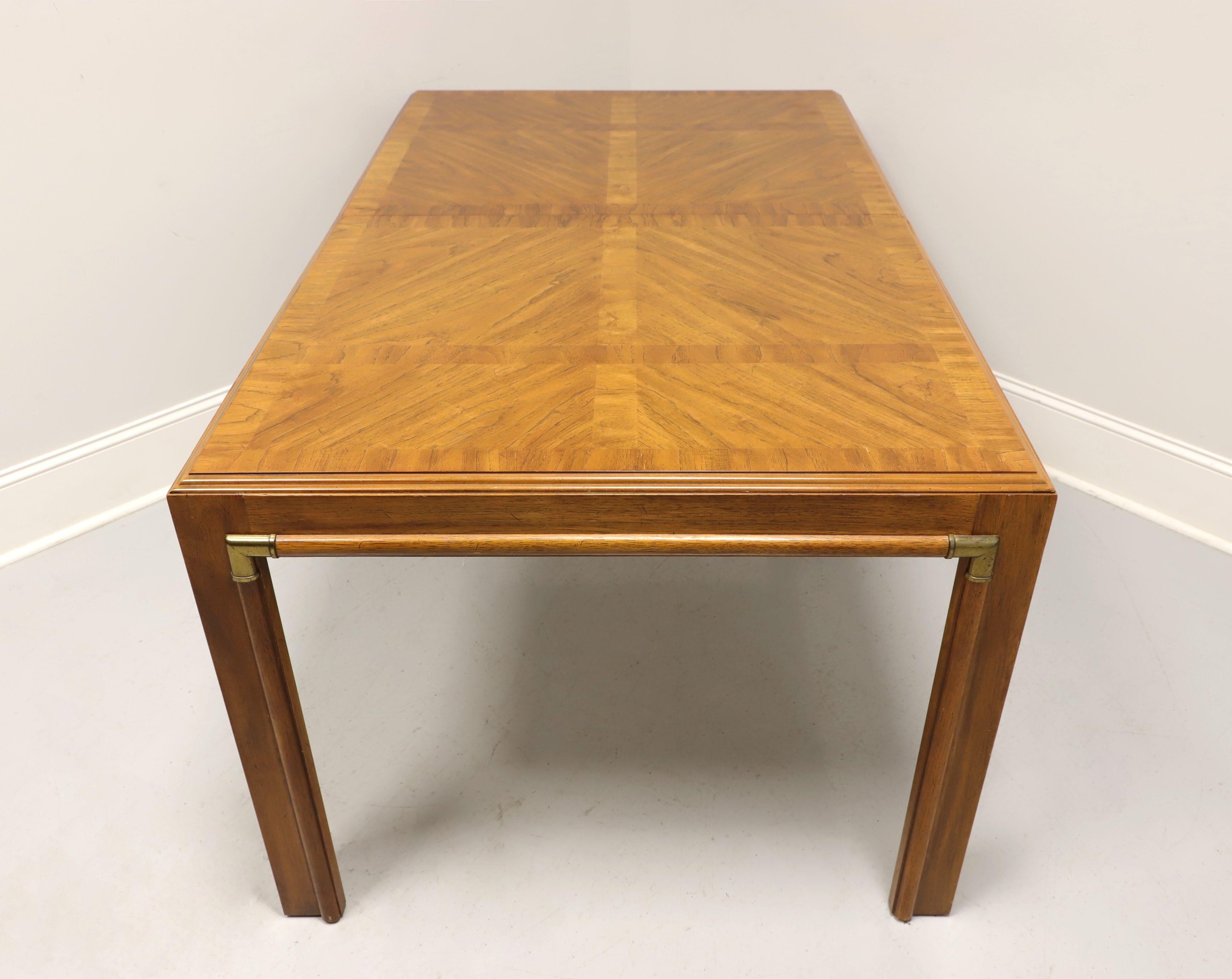 A campaign style rectangular dining table by Drexel, from their Accolade Collection. Pecan with a golden finish, banded top, brass accents and square straight legs. Metal expansion slider. Includes two extension leaves. Made in North Carolina, USA,