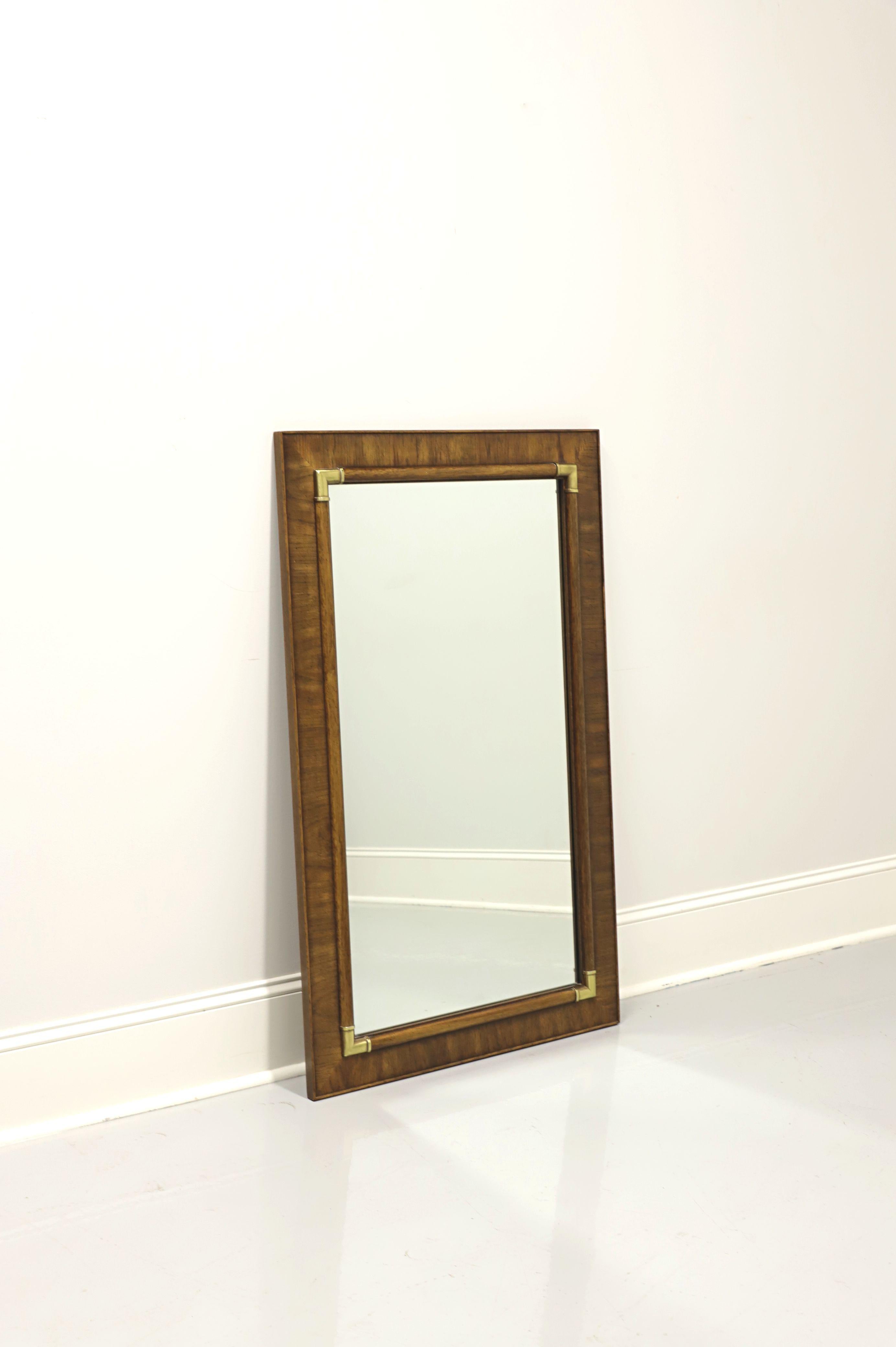A Campaign style wall mirror by Drexel Heritage, from their Accolade collection. Mirror glass and rectangular banded pecan frame with brass accents. Made in North Carolina, USA, circa 1981. 

Style #: 904-210

Measures: 29W 1.25D 47H, Weighs