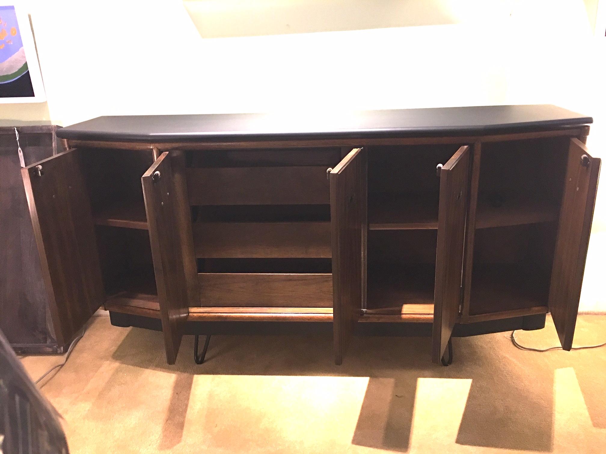 This vintage piece has been refurbished with a matte black top, base, and cool hair pin legs. Doors open to reveal shelves on the side and drawers in the center section providing storage in either a dining room, living room. or bedroom. The piece