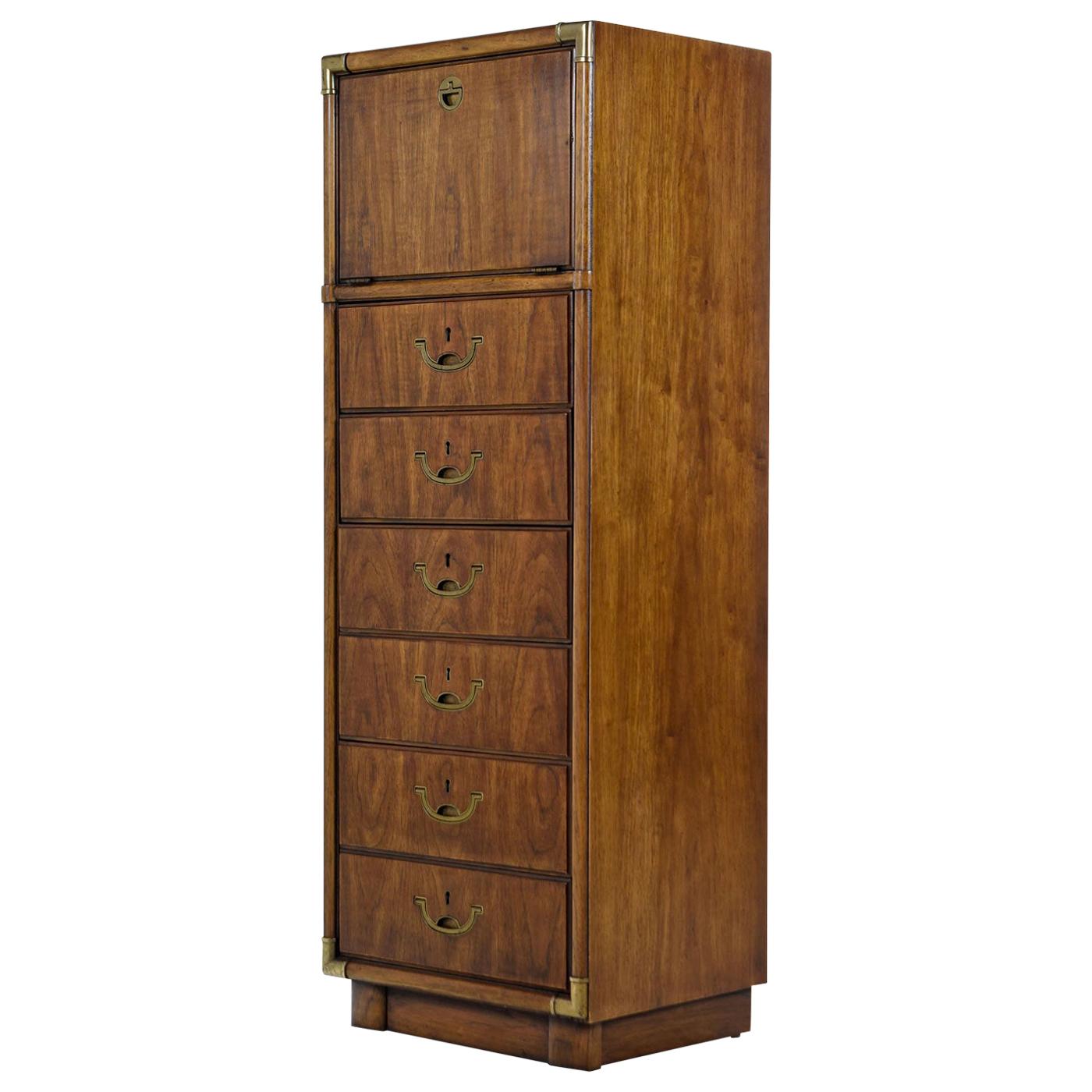 Solid wood Campaign style tall chest of drawers made by esteemed US furniture maker Drexel Heritage in the 1970s. More than just storage, this tall and skinny tower is actually a vanity lingerie chest with a flip topmirror. Three small pull-out